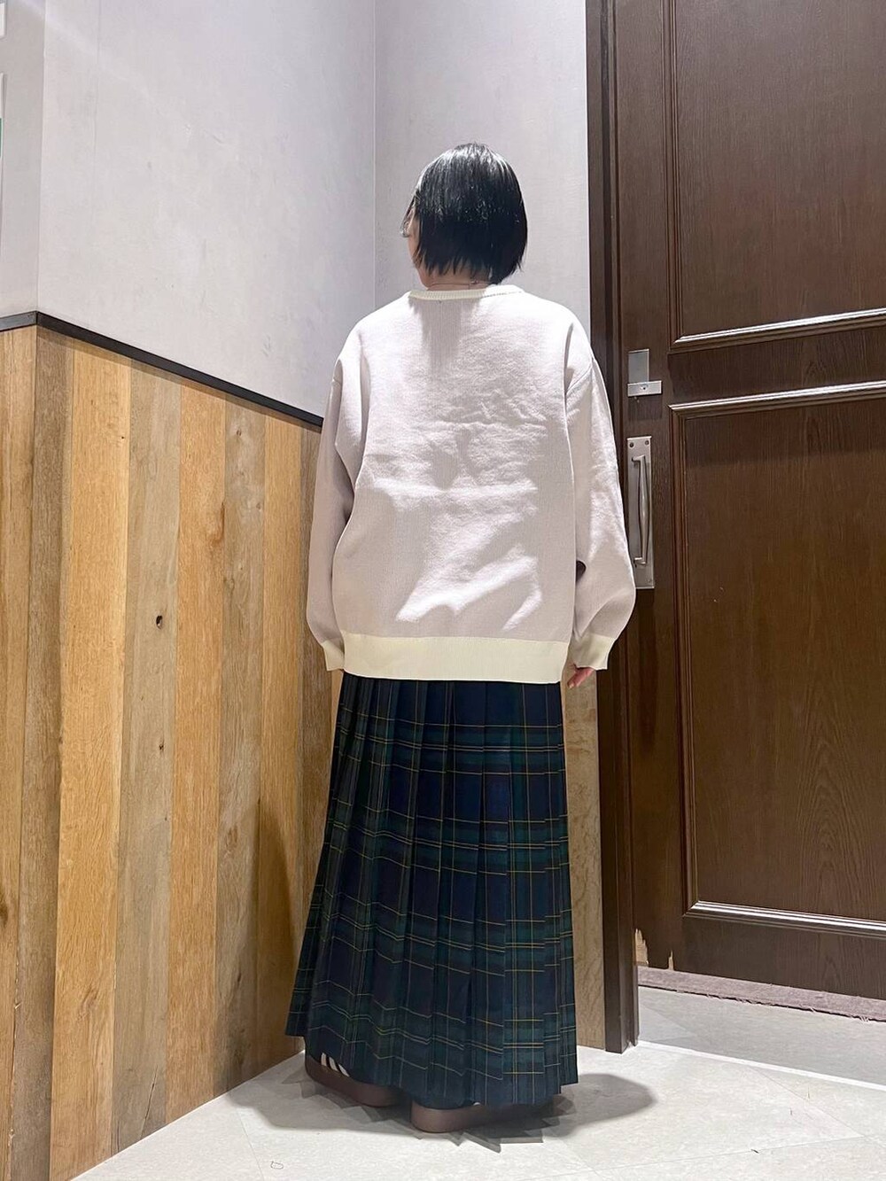 ホワイト系のニット/セーター、グリーン系のスカート、ブラック系のスニーカーを着用したレディースの秋コーディネートの4枚目の写真