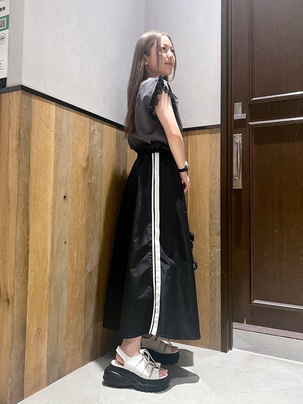 ブラック系のTシャツ/カットソー、ゴールド系のハンドバッグ、ブラック系のサンダルを着用したレディースの夏コーディネートの2枚目の写真