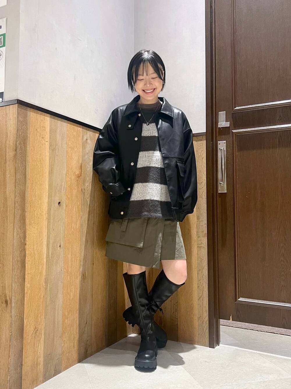 ブラック系のブーツ、ホワイト系のニット/セーター、ブラック系のブルゾンを着用したレディースの秋コーディネートの5枚目の写真