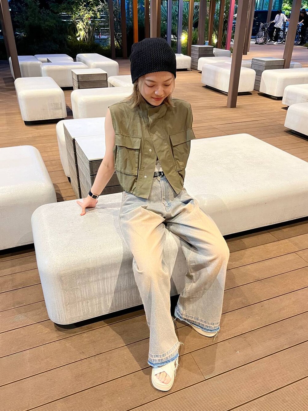 グリーン系のベスト、ホワイト系のキャミソール、ブルー系のデニムパンツを着用したレディースの夏コーディネートの3枚目の写真