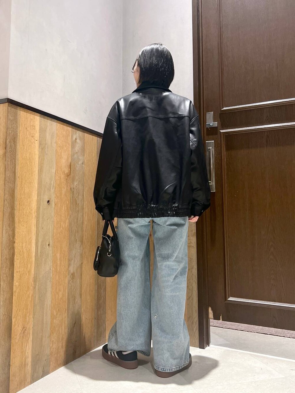 ブルー系のデニムパンツ、ブラック系のショルダーバッグ、ブラック系のブルゾンを着用したレディースの秋コーディネートの3枚目の写真