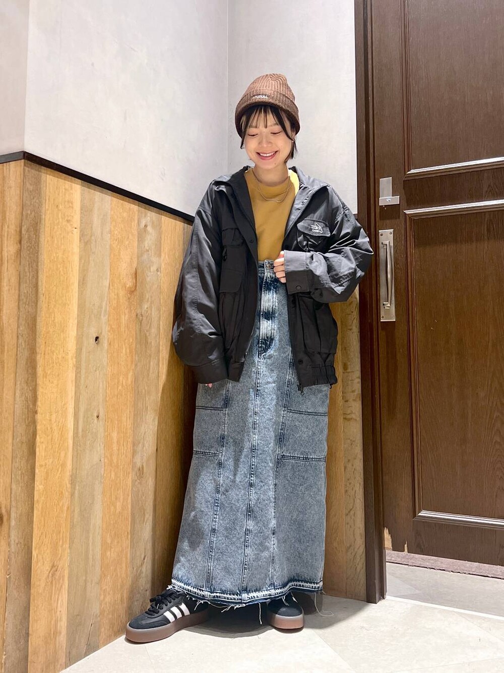 ブルー系のデニムスカート、ブラック系のブルゾン、イエロー系のスウェットを着用したレディースの秋コーディネートの5枚目の写真