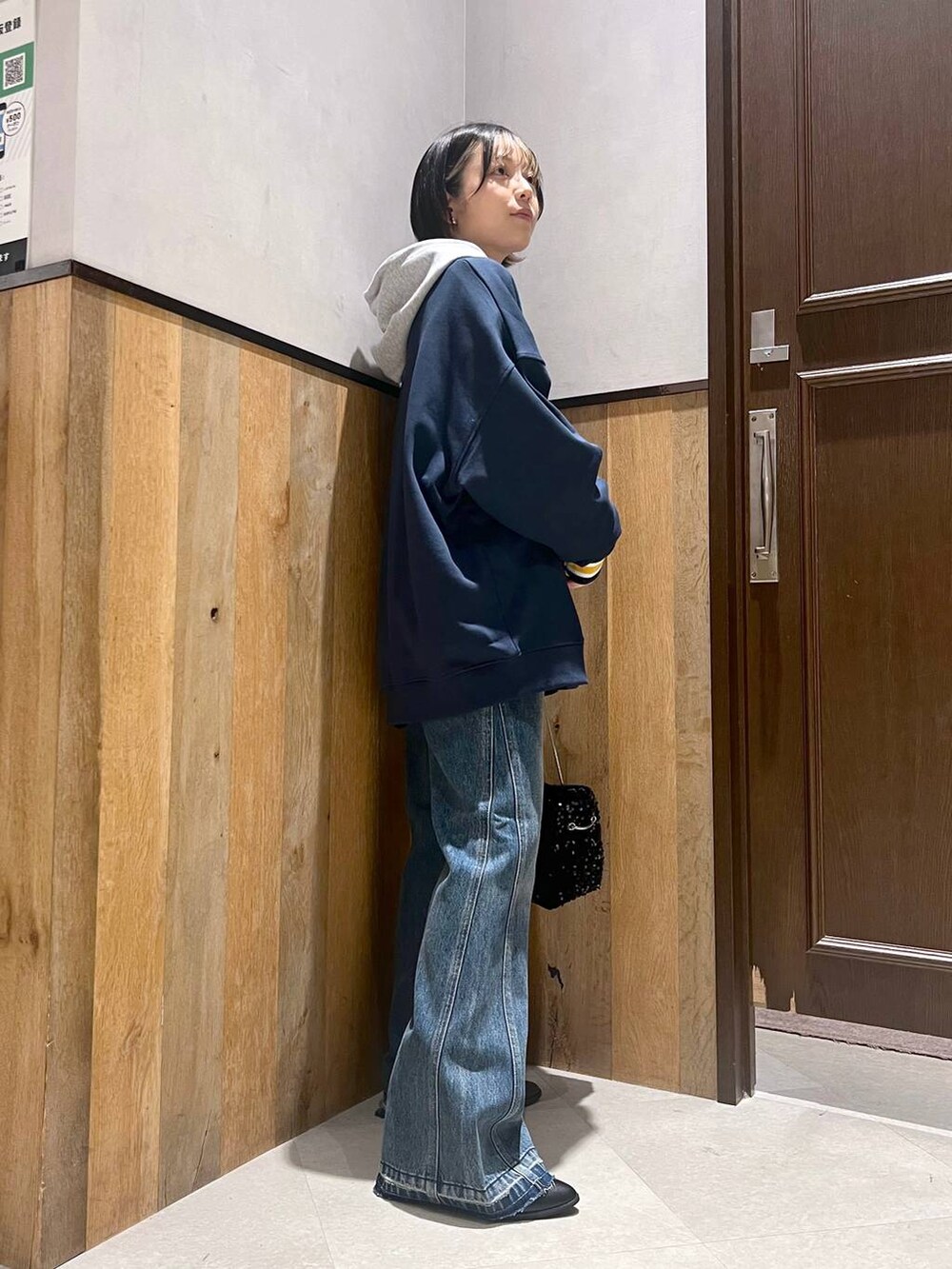 ブルー系のスウェット、ブルー系のデニムパンツ、グレー系のパーカーを着用したレディースの秋コーディネートの2枚目の写真
