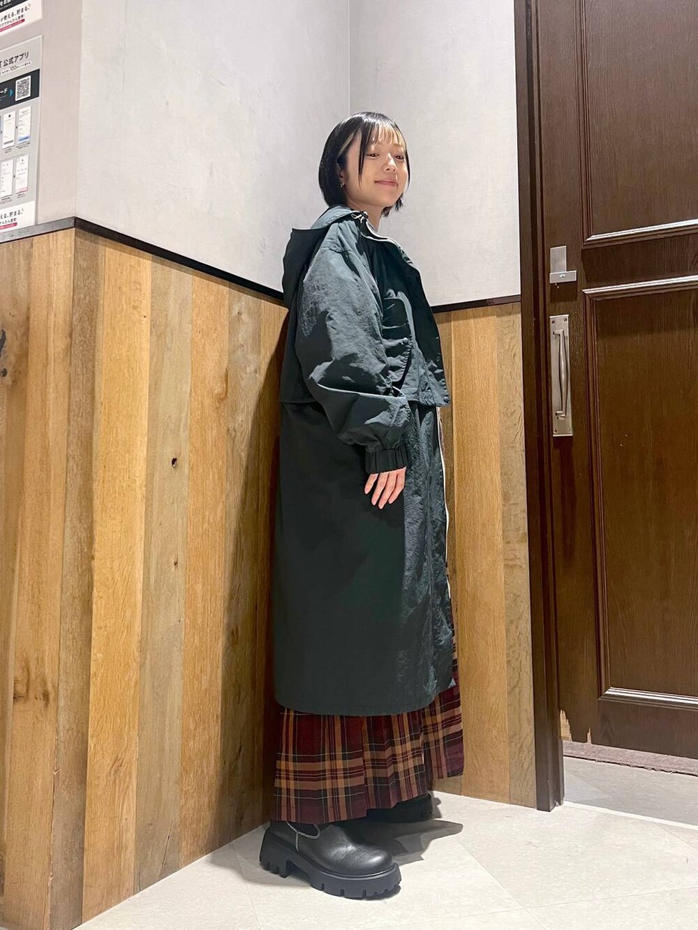 グリーン系のニット/セーター、ブラック系のブーツ、ブルー系のショルダーバッグを着用したレディースの秋コーディネートの5枚目の写真