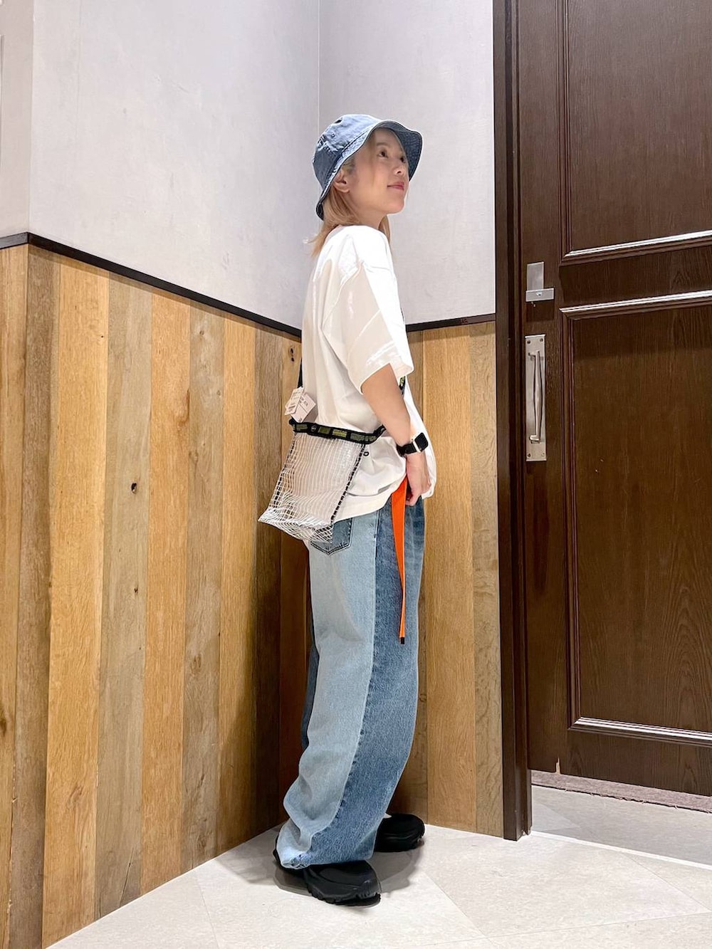 ブラック系のスニーカー、ブルー系のデニムパンツ、ブラック系のショルダーバッグを着用したレディースの秋コーディネートの2枚目の写真