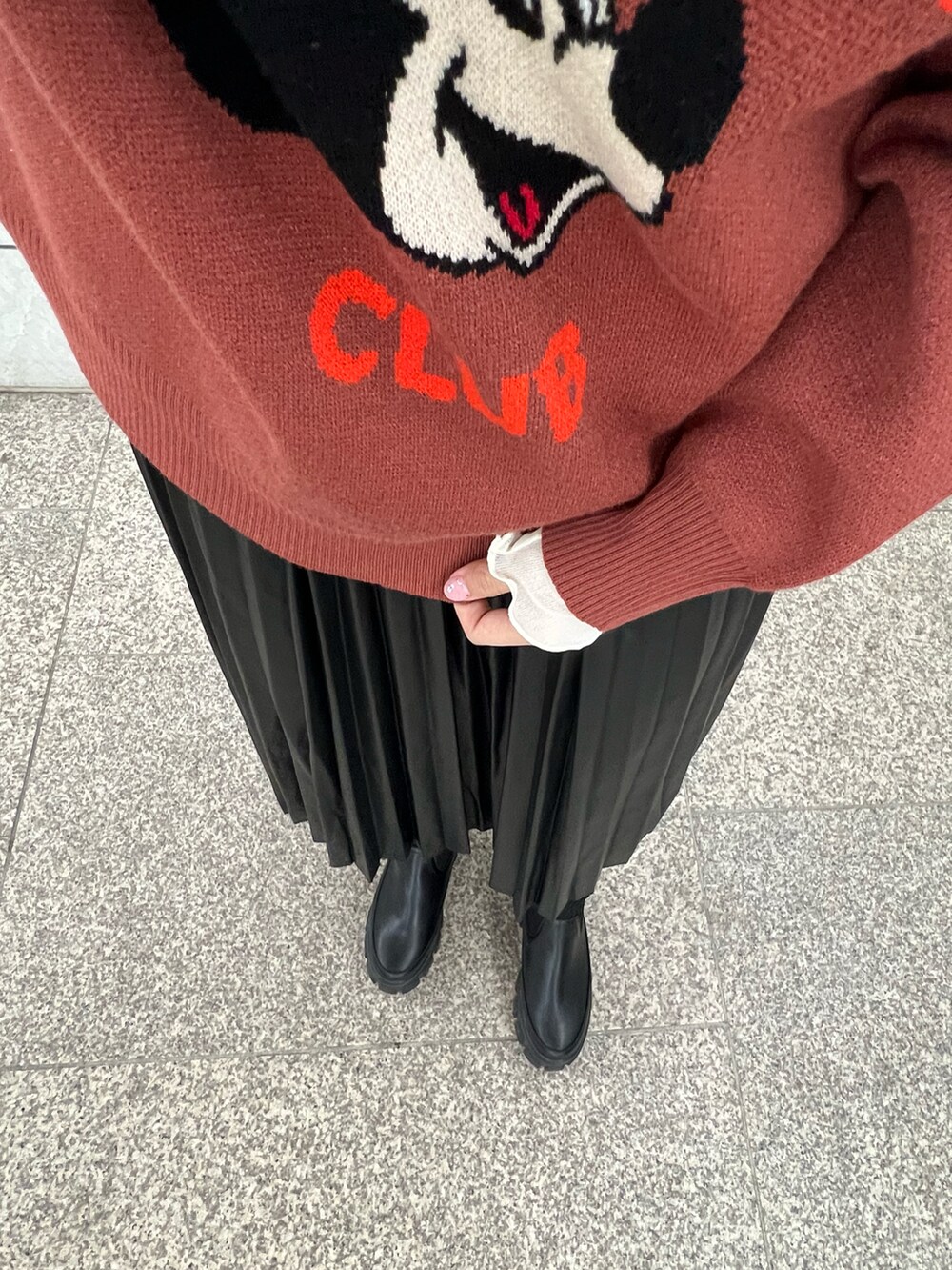 レッド系のニット/セーター、ブラック系のスカート、ホワイト系のTシャツ/カットソーを着用したレディースの秋コーディネートの3枚目の写真