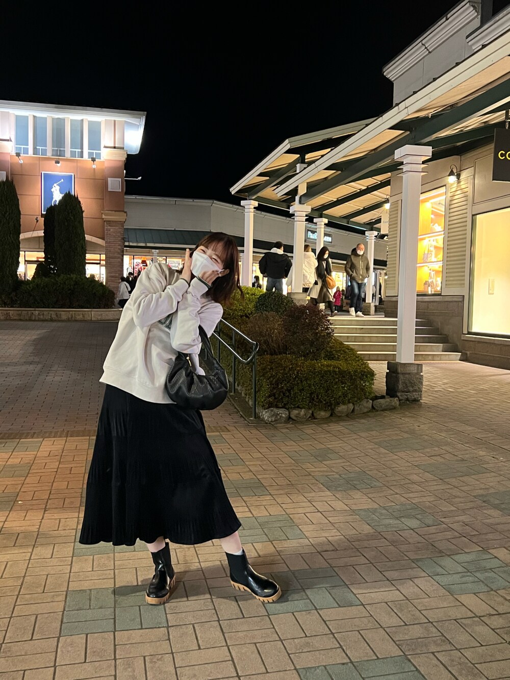 ブラック系のスカート、ブラック系のブーツ、ブラック系のハンドバッグを着用したレディースの冬コーディネートの2枚目の写真