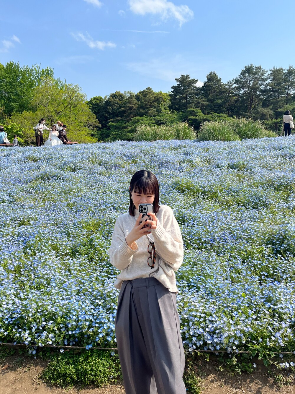 ベージュ系のニット/セーター、グレー系のスラックス、ブラック系のスニーカーを着用したレディースの春コーディネートの3枚目の写真