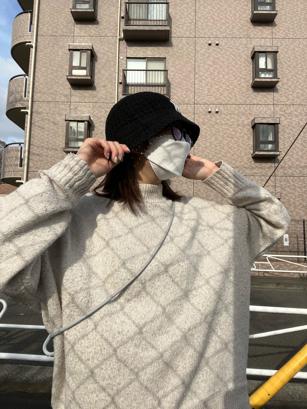 グレー系のスラックス、ベージュ系のニット/セーター、ホワイト系のスニーカーを着用したレディースの春コーディネートの3枚目の写真