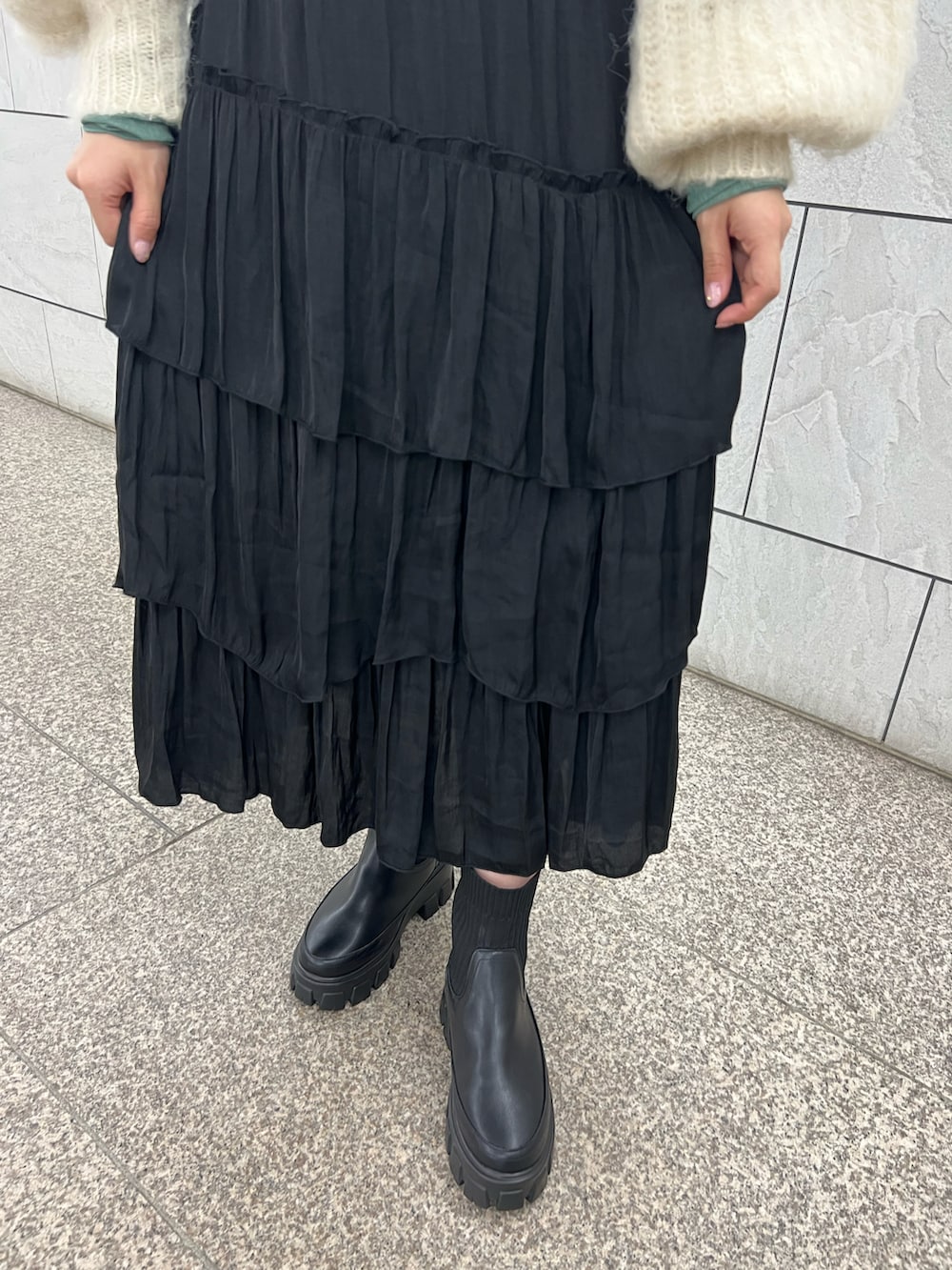 ブラック系のスカート、ブラック系のブーツ、ホワイト系のニット/セーターを着用したレディースの秋コーディネートの3枚目の写真