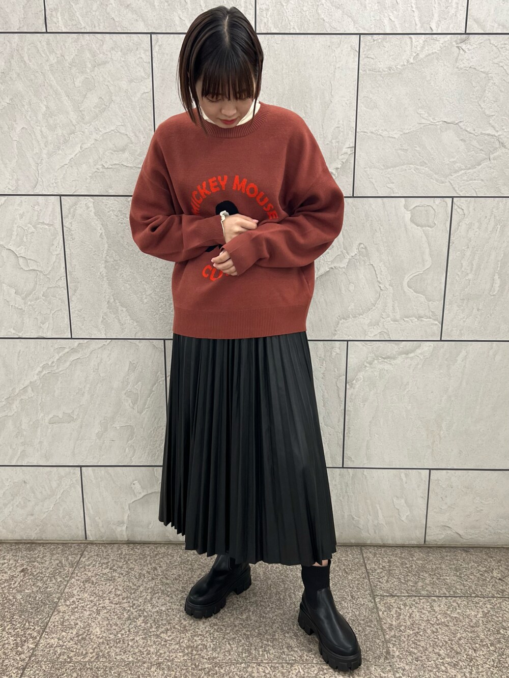 レッド系のニット/セーター、ブラック系のスカート、ホワイト系のTシャツ/カットソーを着用したレディースの秋コーディネートの2枚目の写真