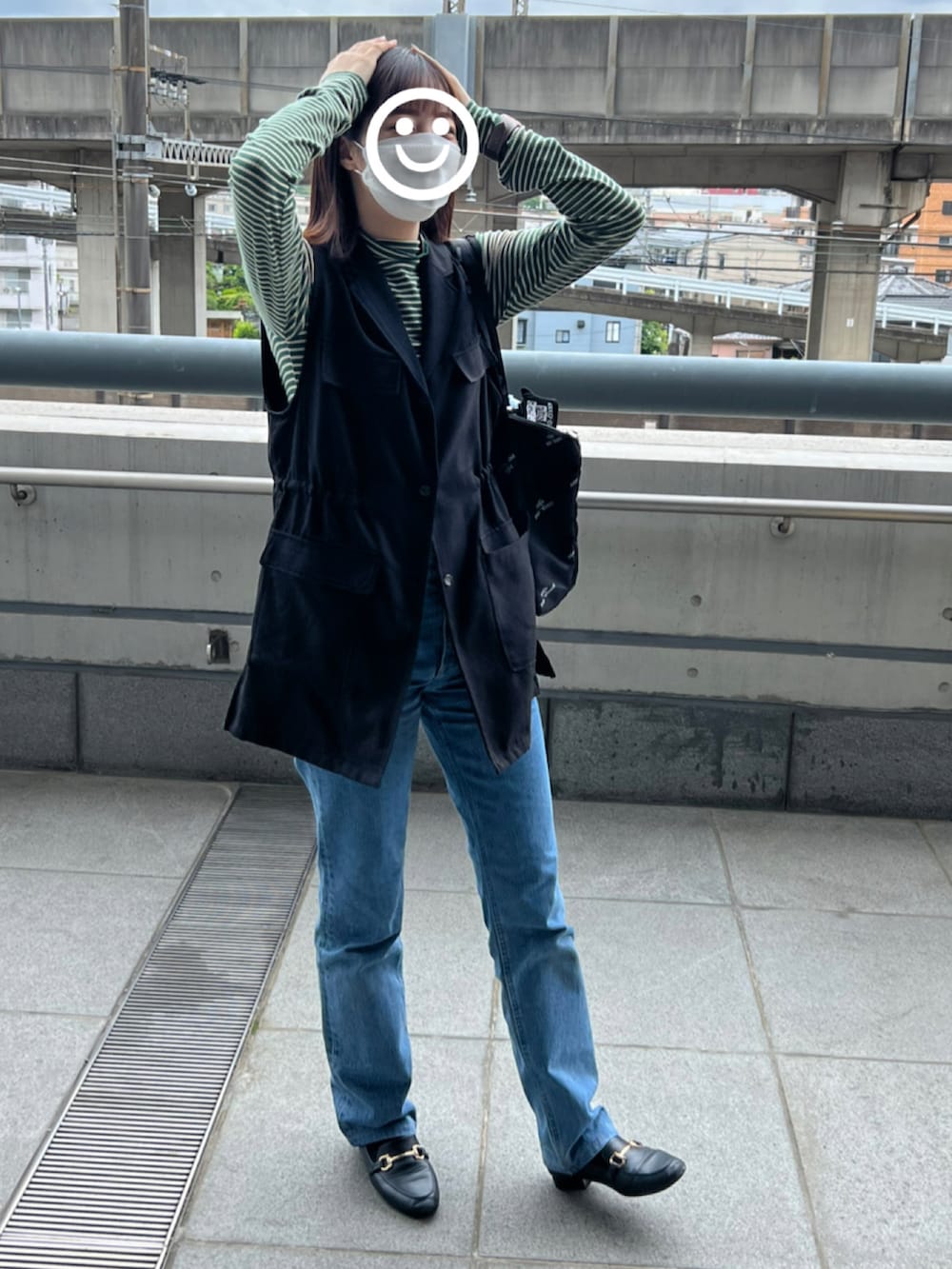 ブルー系のデニムパンツ、ブラック系のローファー、ブラック系のベストを着用したレディースの春コーディネートの2枚目の写真