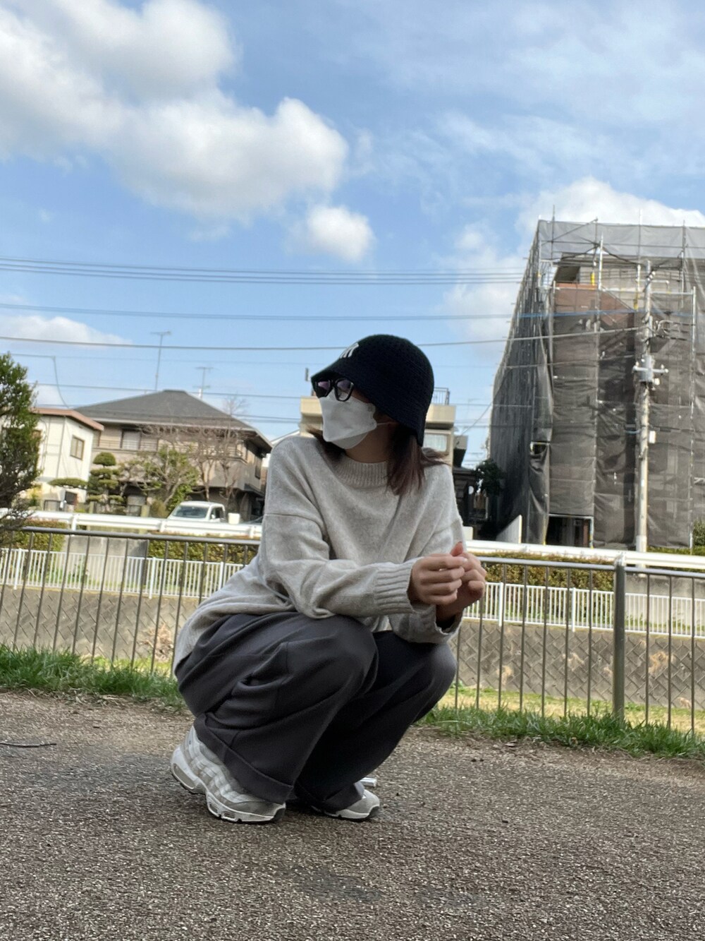 グレー系のスラックス、ベージュ系のニット/セーター、ホワイト系のスニーカーを着用したレディースの春コーディネートの2枚目の写真