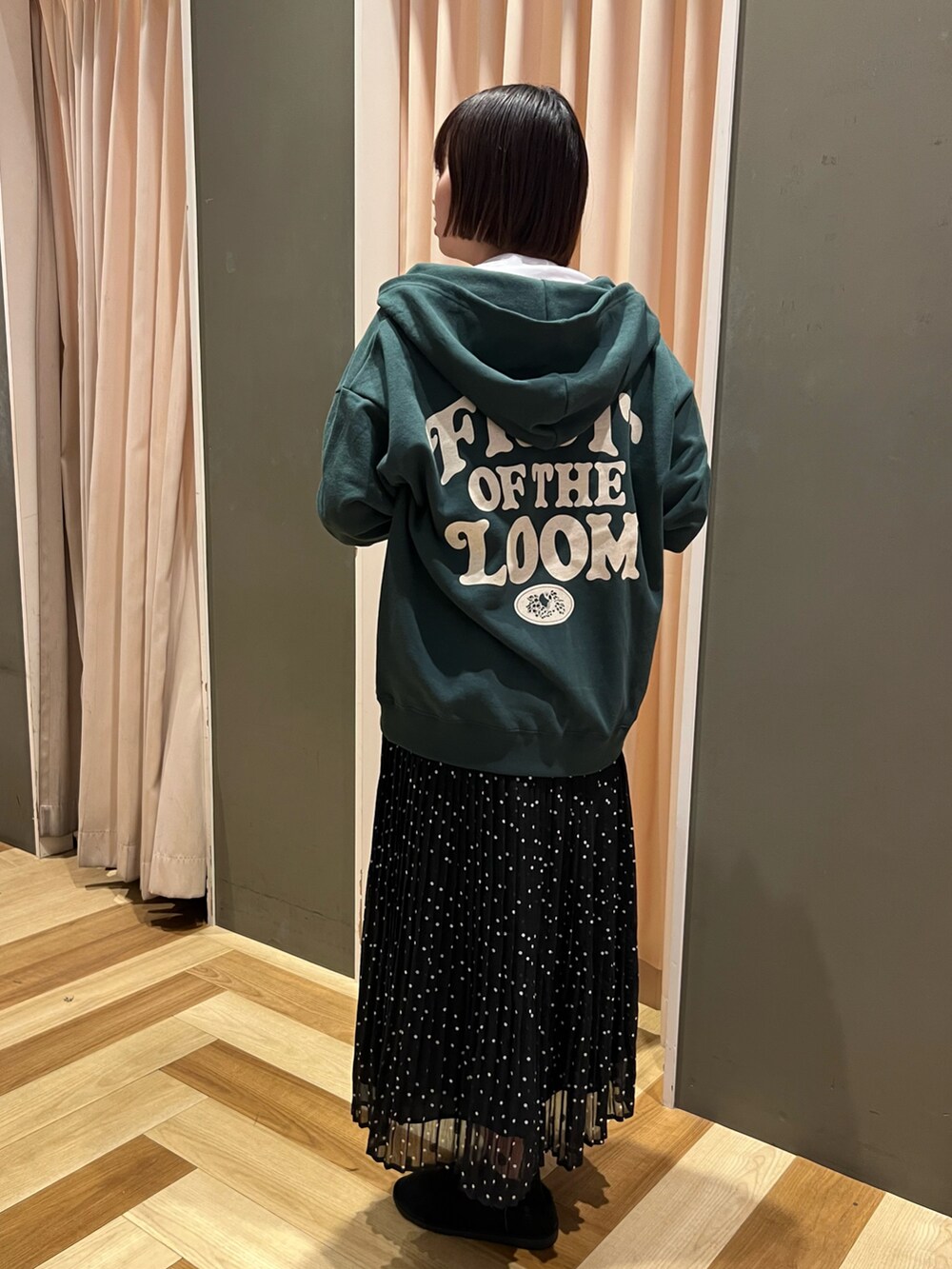 グリーン系のパーカー、ホワイト系のTシャツ/カットソー、ブラック系のスカートを着用したレディースの秋コーディネートの2枚目の写真