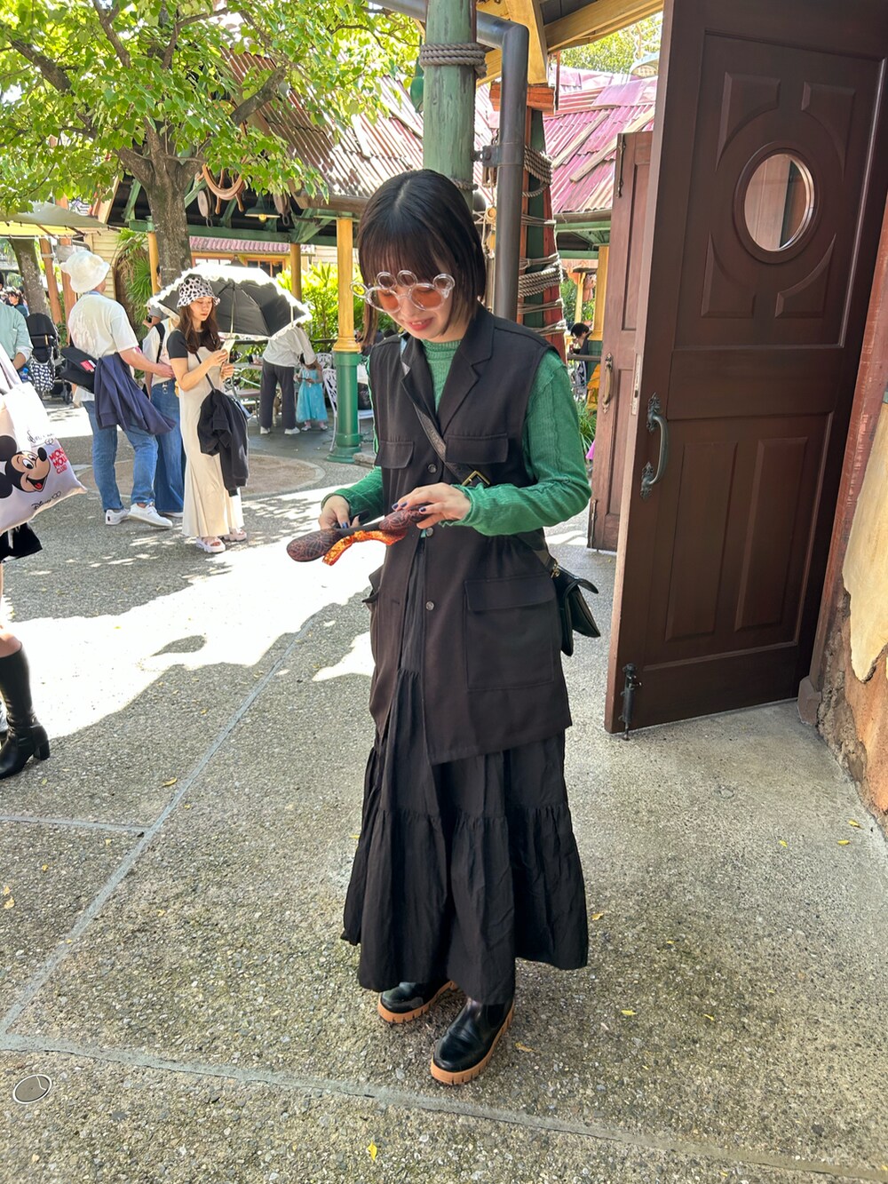 ブラック系のショルダーバッグ、ブラック系のベスト、ブラック系のスカートを着用したレディースの秋コーディネートの2枚目の写真