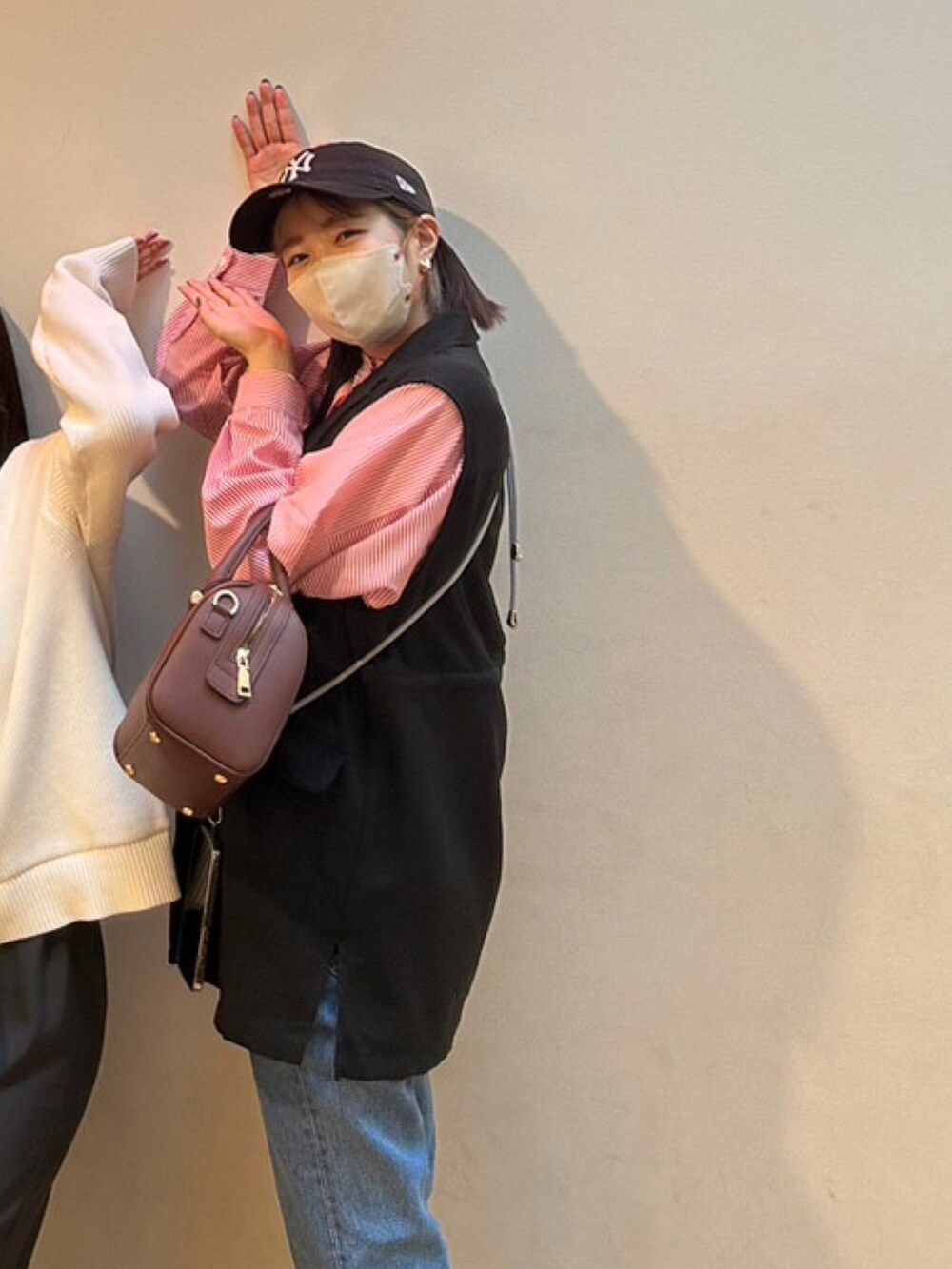 ブラウン系のボストンバッグ、ブラック系のベスト、ブルー系のデニムパンツを着用したレディースの秋コーディネートの2枚目の写真