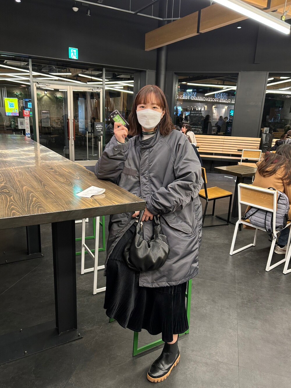 ブラック系のハンドバッグ、グレー系のその他アウター、ブラック系のスカートを着用したレディースの冬コーディネートの2枚目の写真