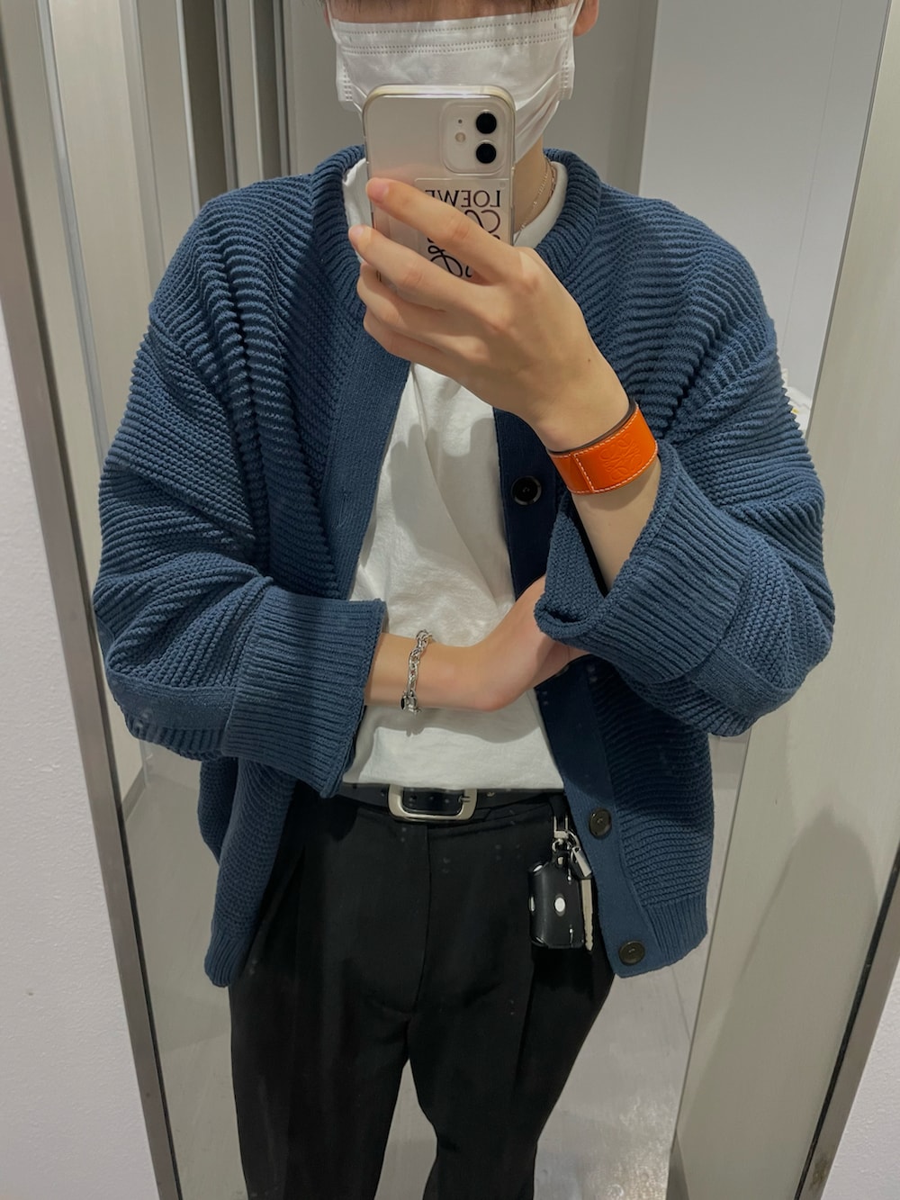 ブラック系のスラックス、ブルー系のカーディガン/ボレロ、オレンジ系のバングル/リストバンドを着用したメンズの春コーディネートの2枚目の写真