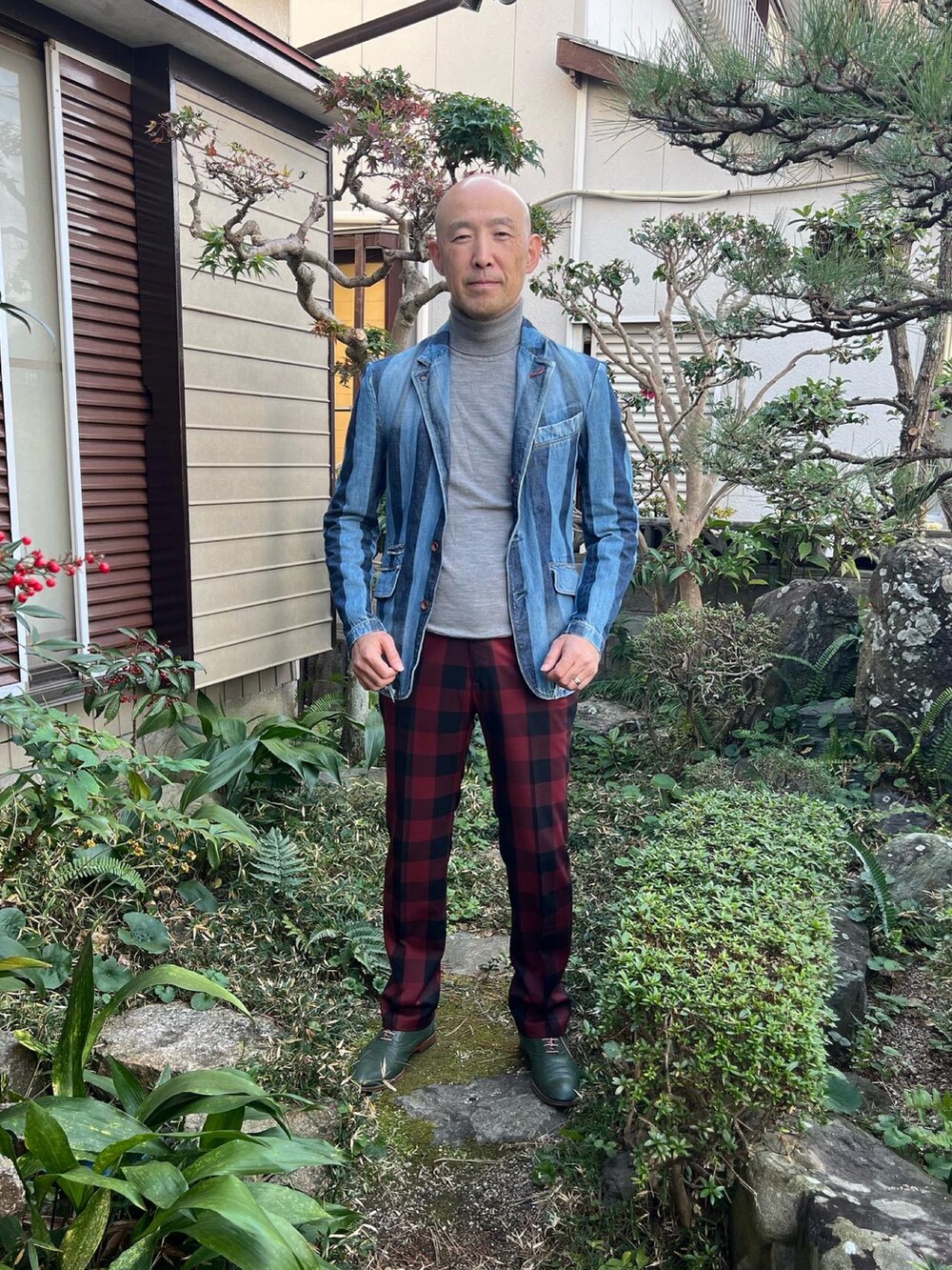 グレー系のニット/セーター、ブルー系のデニムジャケット、レッド系のスラックスを着用したメンズの冬コーディネートの2枚目の写真