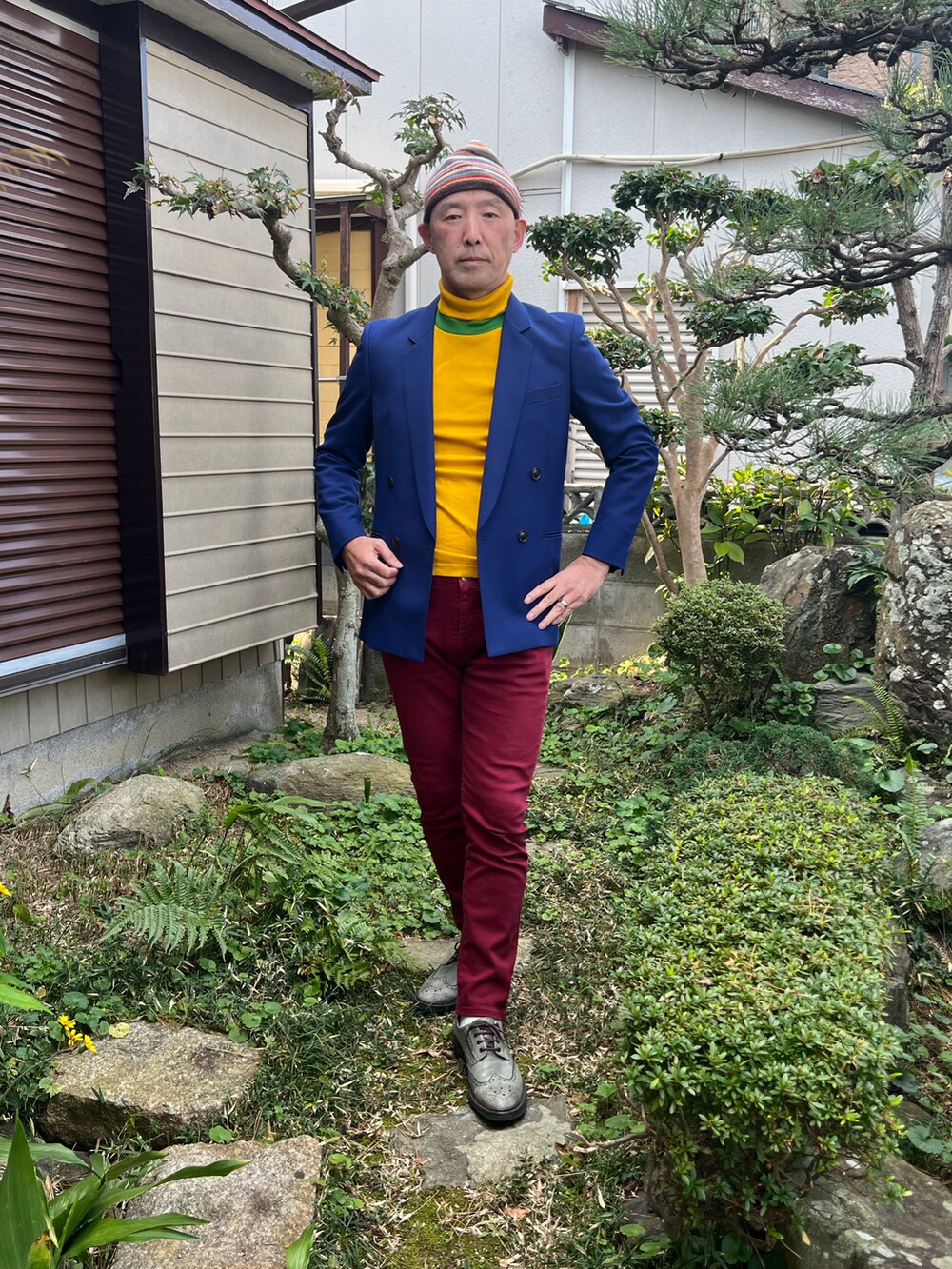 ブルー系のテーラードジャケット、グレー系のドレスシューズ、レッド系のデニムパンツを着用したメンズの冬コーディネートの2枚目の写真