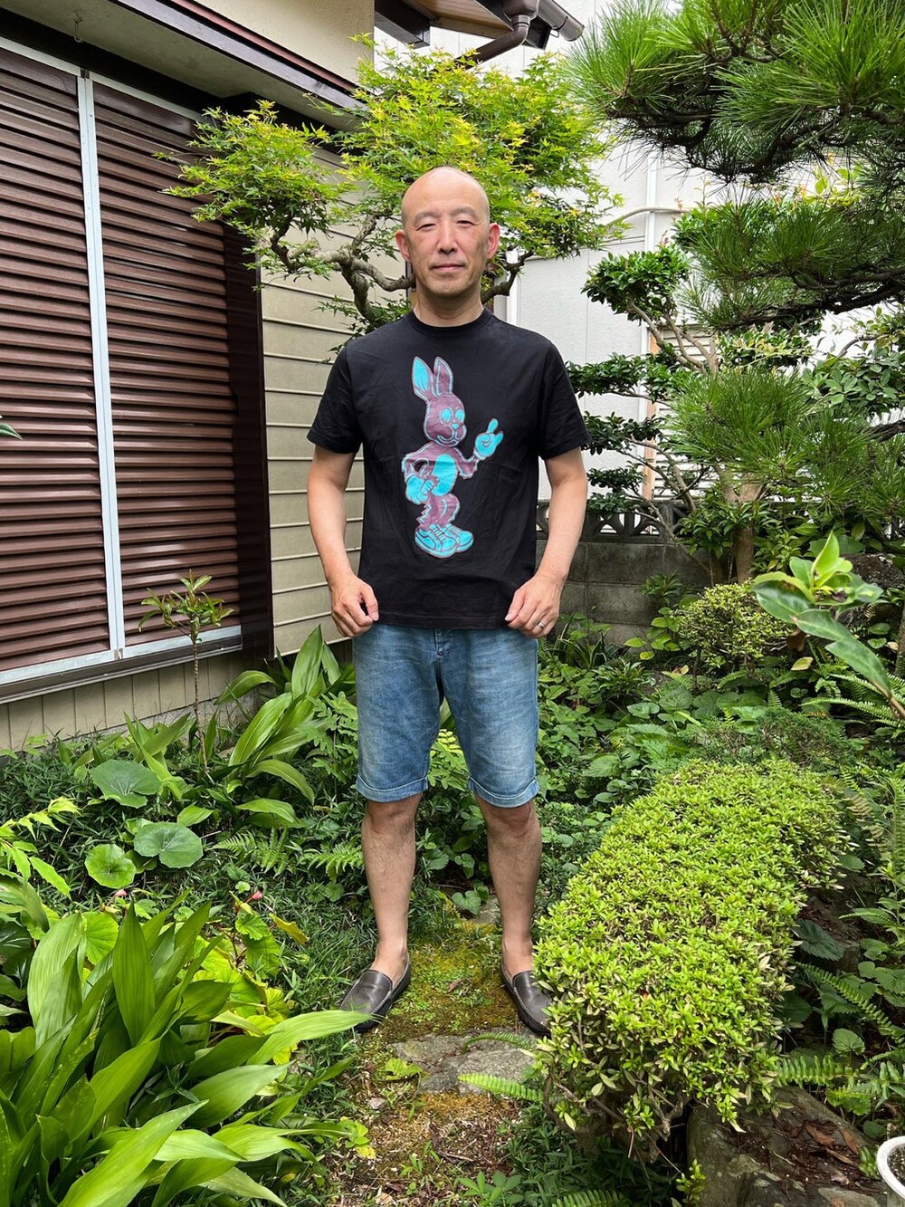 ブラック系のTシャツ/カットソー、ブルー系のデニムパンツ、ブルー系のローファーを着用したメンズの夏コーディネートの2枚目の写真