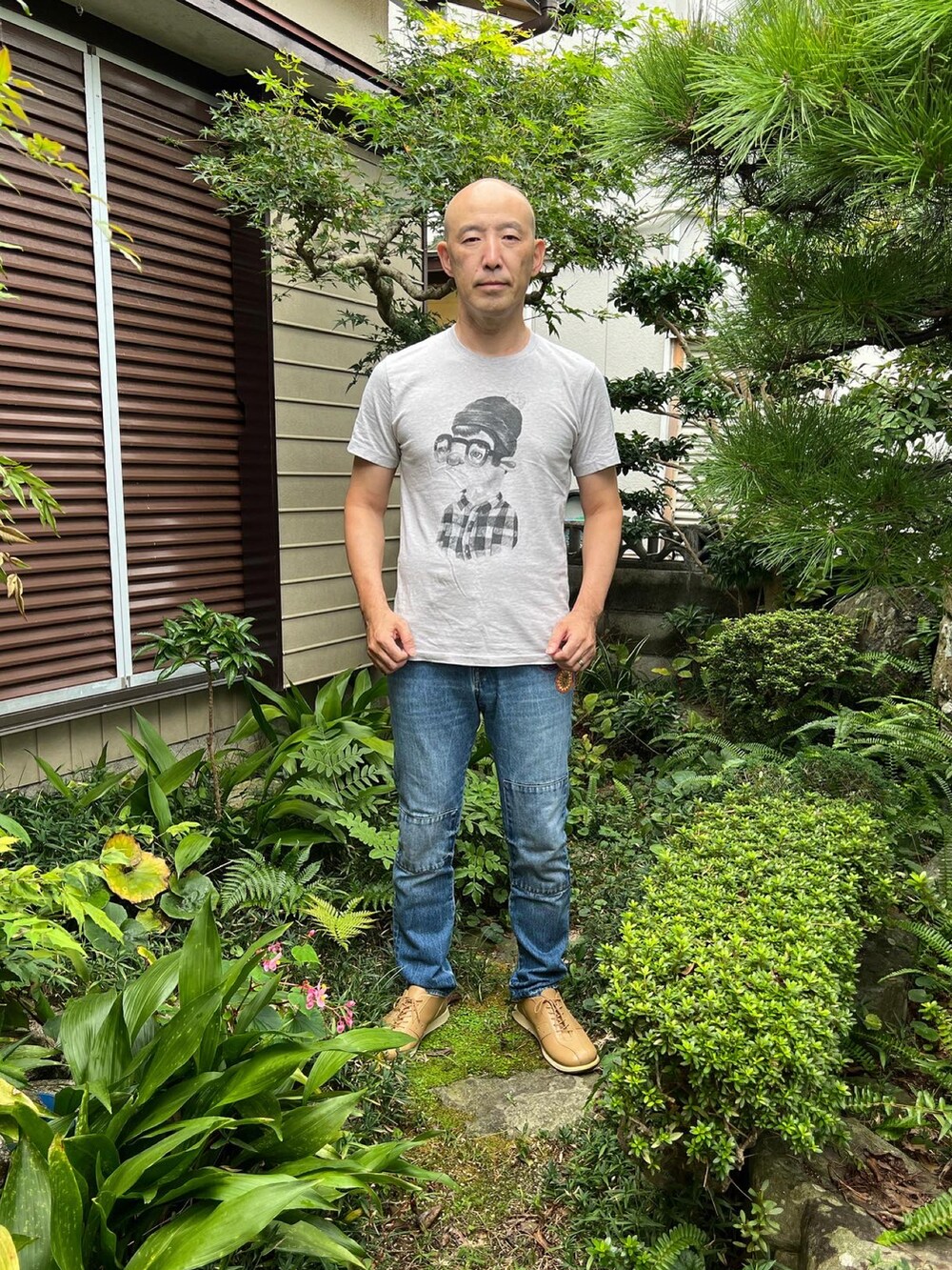 グレー系のTシャツ/カットソー、ブルー系のデニムパンツ、ベージュ系のスニーカーを着用したメンズの秋コーディネートの2枚目の写真