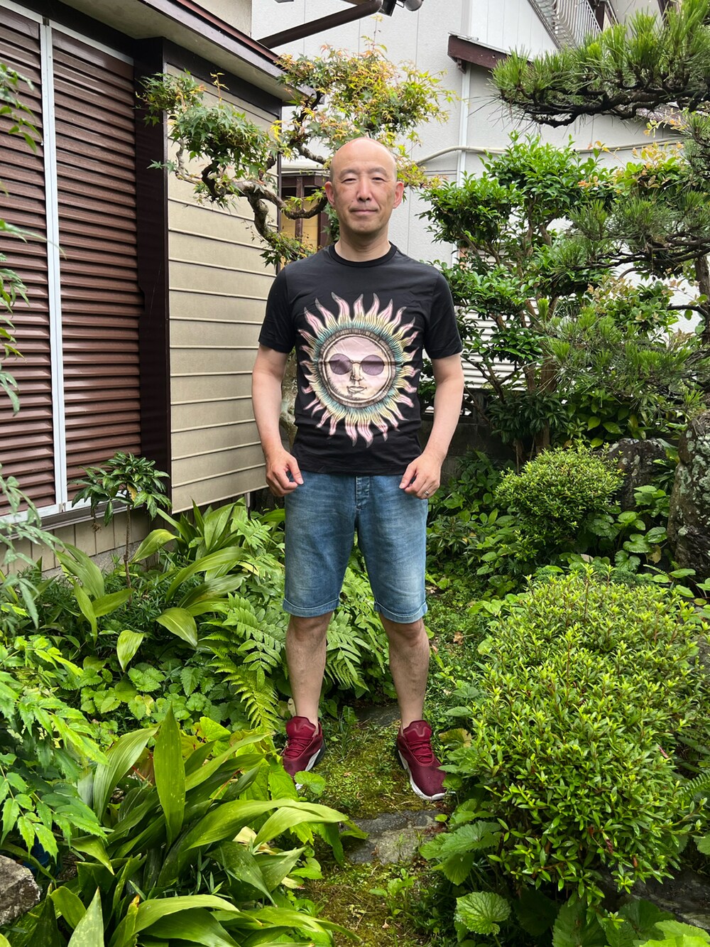 ブラック系のTシャツ/カットソー、ブルー系のデニムパンツ、レッド系のスニーカーを着用したメンズの夏コーディネートの2枚目の写真