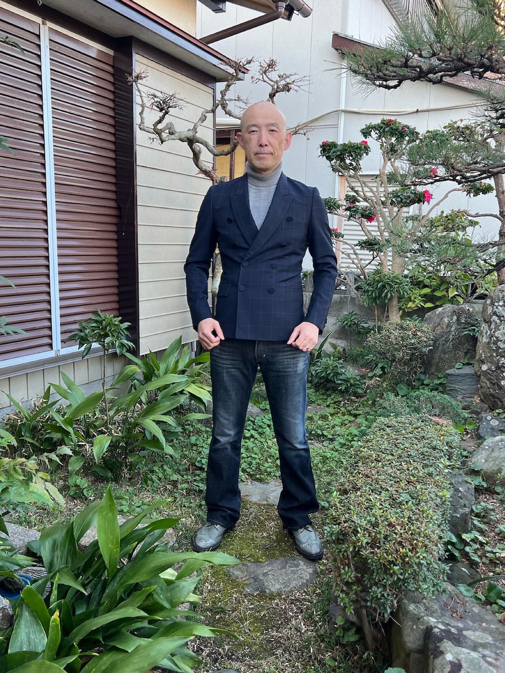 ブラック系のテーラードジャケット、ブラック系のデニムパンツ、グレー系のドレスシューズを着用したメンズの冬コーディネートの2枚目の写真