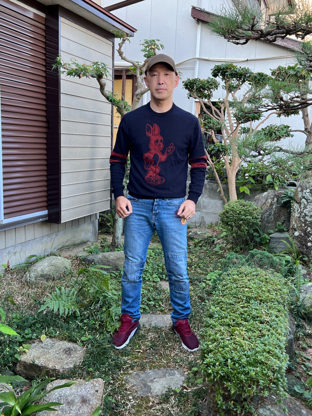 ブルー系のニット/セーター、ブルー系のデニムパンツ、レッド系のスニーカーを着用したメンズの秋コーディネートの2枚目の写真