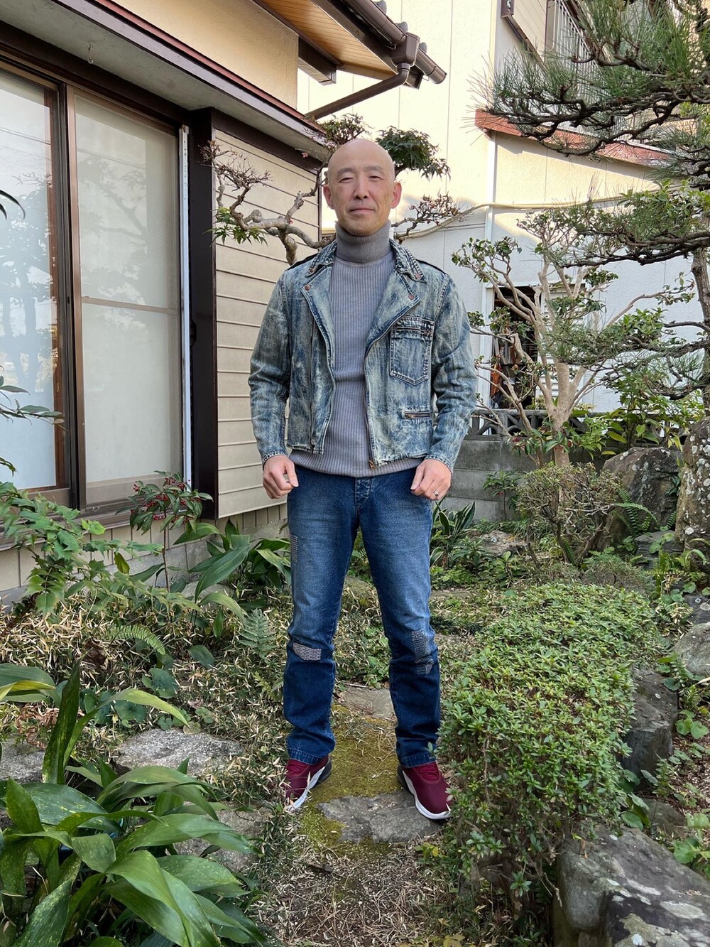 ブルー系のライダースジャケット、グレー系のニット/セーター、ブルー系のデニムパンツを着用したメンズの冬コーディネートの2枚目の写真