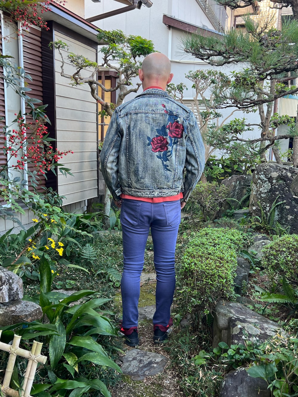 ブルー系のライダースジャケット、オレンジ系のTシャツ/カットソー、ブルー系のデニムパンツを着用したメンズの秋コーディネートの3枚目の写真