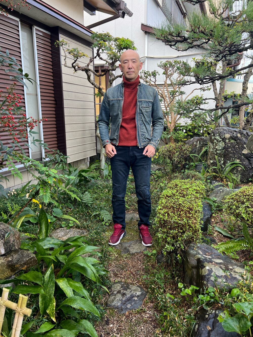 ブラック系のデニムパンツ、レッド系のスニーカー、ブルー系のライダースジャケットを着用したメンズの秋コーディネートの2枚目の写真