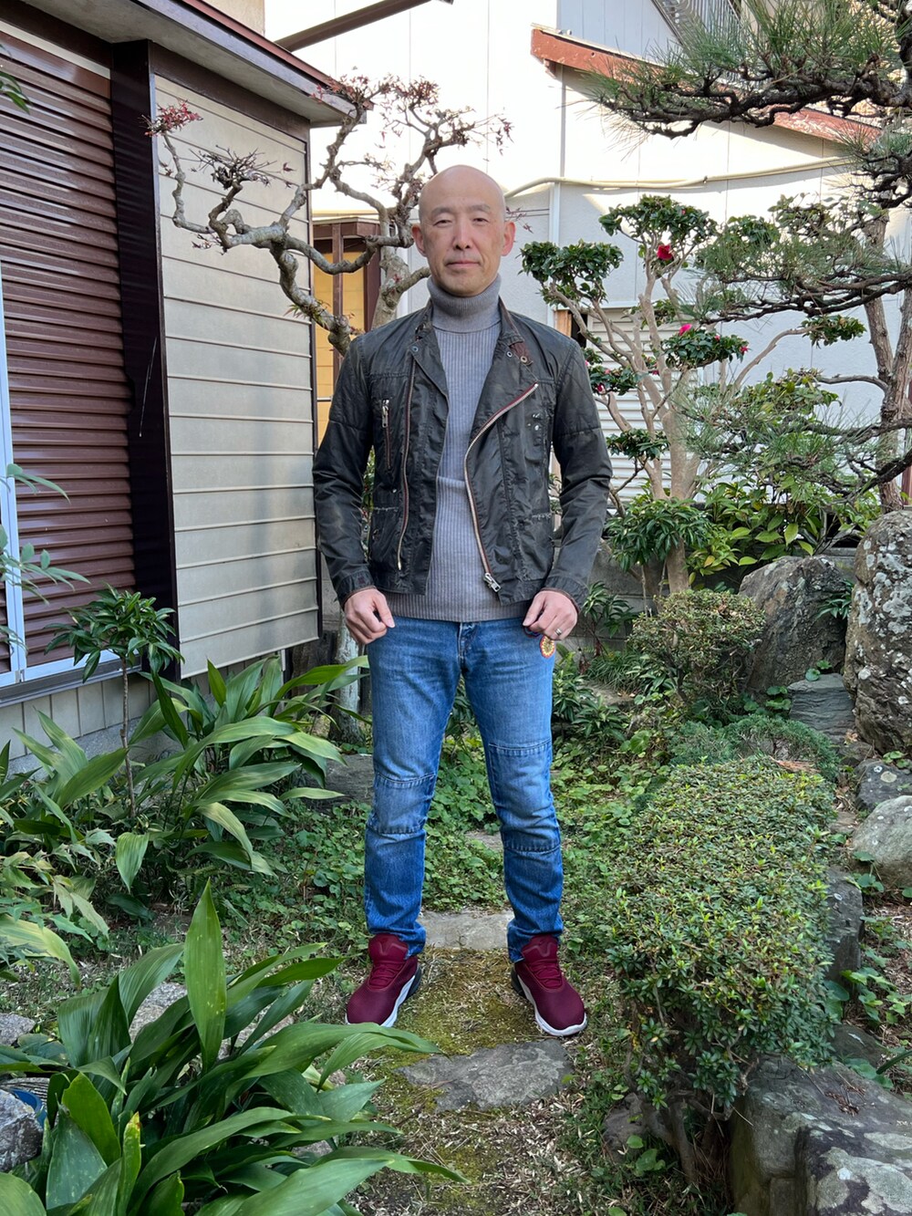 グレー系のニット/セーター、グレー系のライダースジャケット、ブルー系のデニムパンツを着用したメンズの冬コーディネートの2枚目の写真