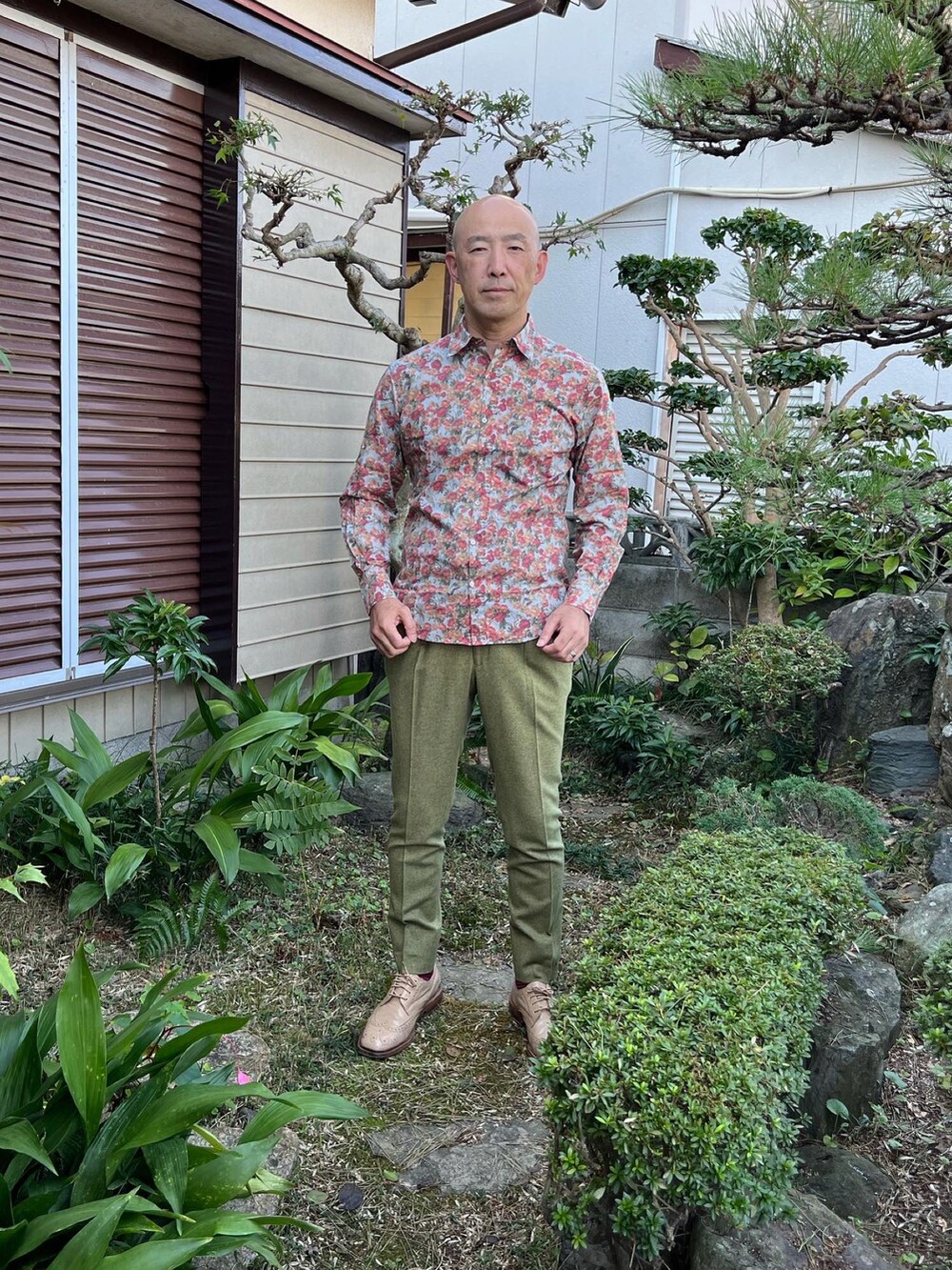 ブルー系のシャツ/ブラウス、グリーン系のスラックス、ベージュ系のドレスシューズを着用したメンズの秋コーディネートの2枚目の写真