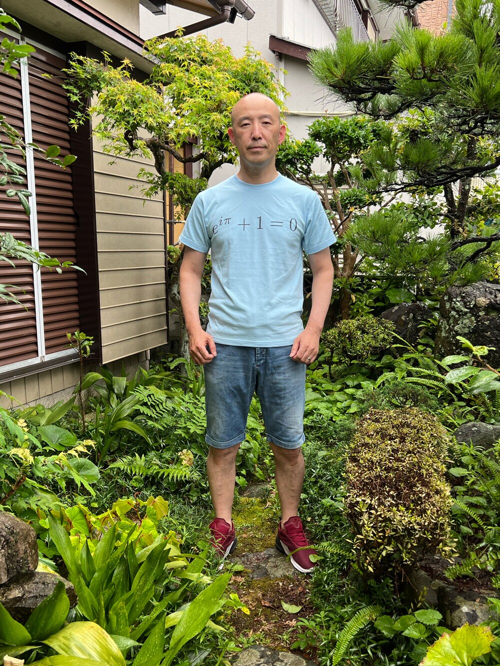 ブルー系のTシャツ/カットソー、ブルー系のデニムパンツ、レッド系のスニーカーを着用したメンズの夏コーディネートの2枚目の写真