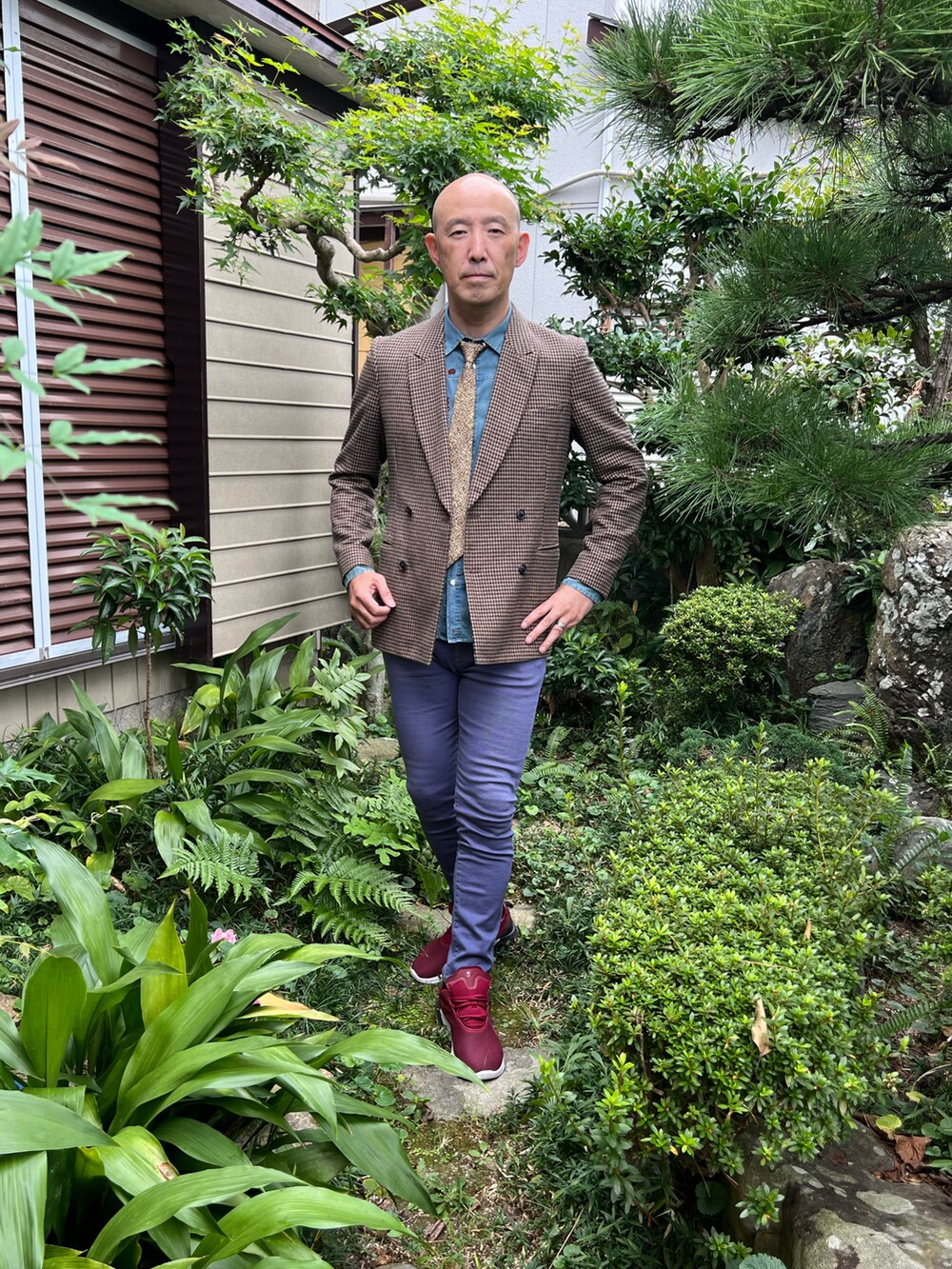 ベージュ系のテーラードジャケット、ブルー系のデニムパンツ、レッド系のスニーカーを着用したメンズの秋コーディネートの2枚目の写真