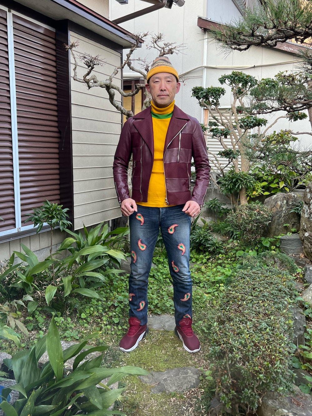 イエロー系のTシャツ/カットソー、レッド系のライダースジャケット、ブルー系のデニムパンツを着用したメンズの春コーディネートの2枚目の写真