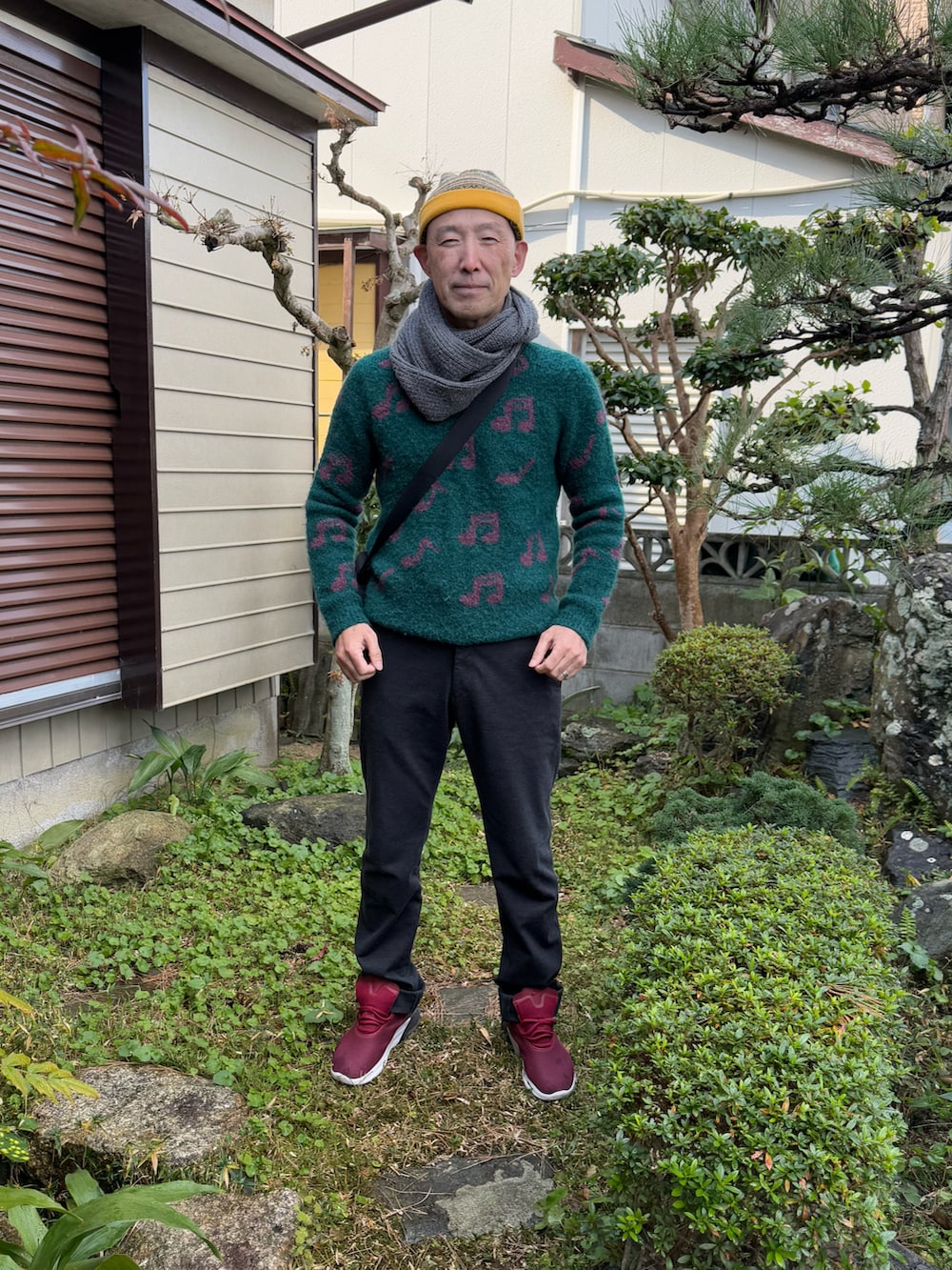 グリーン系のニット/セーター、ブルー系のデニムパンツ、レッド系のスニーカーを着用したメンズの冬コーディネートの2枚目の写真