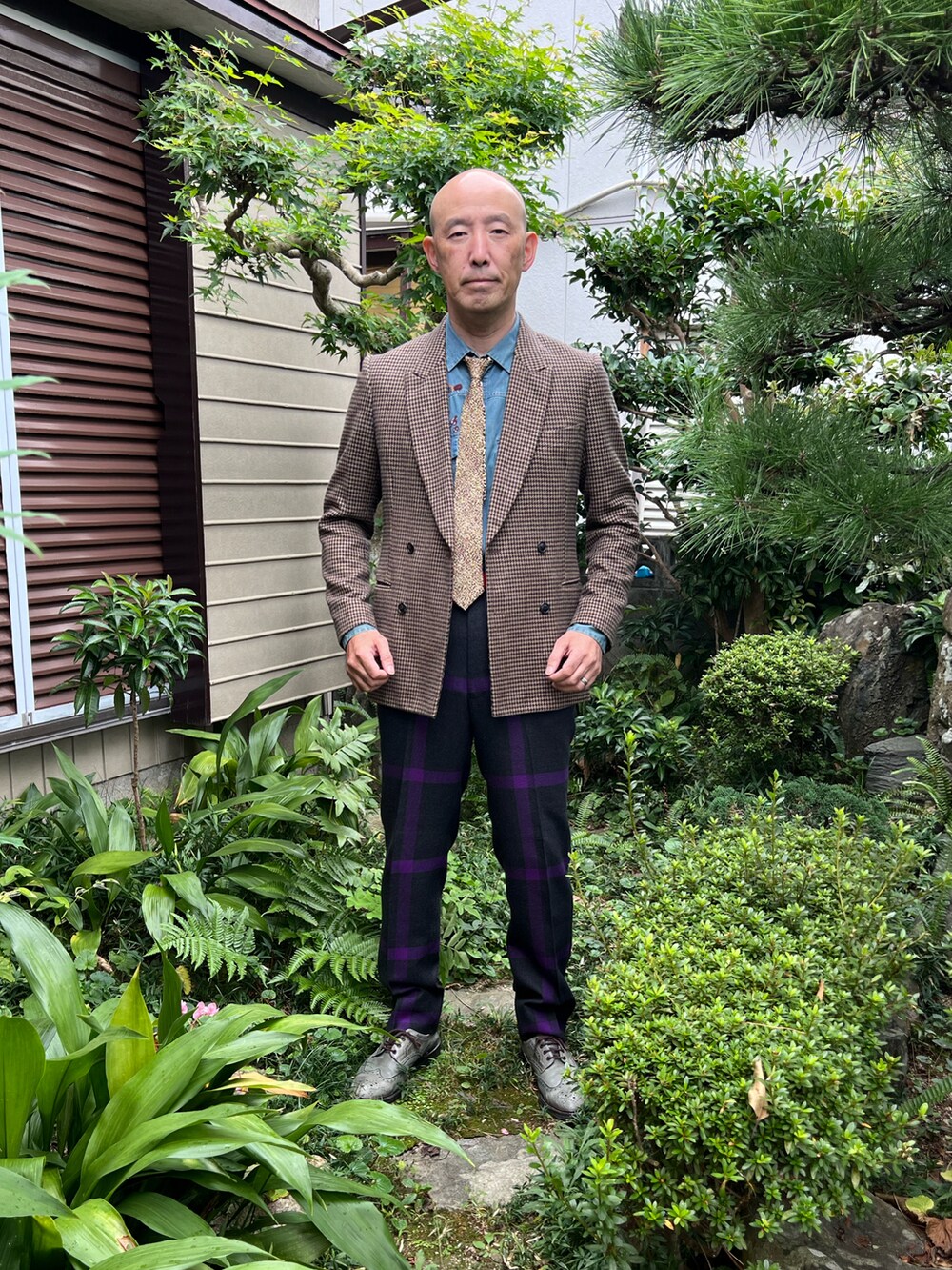 ベージュ系のテーラードジャケット、パープル系のパンツ、グレー系のドレスシューズを着用したメンズの秋コーディネートの3枚目の写真