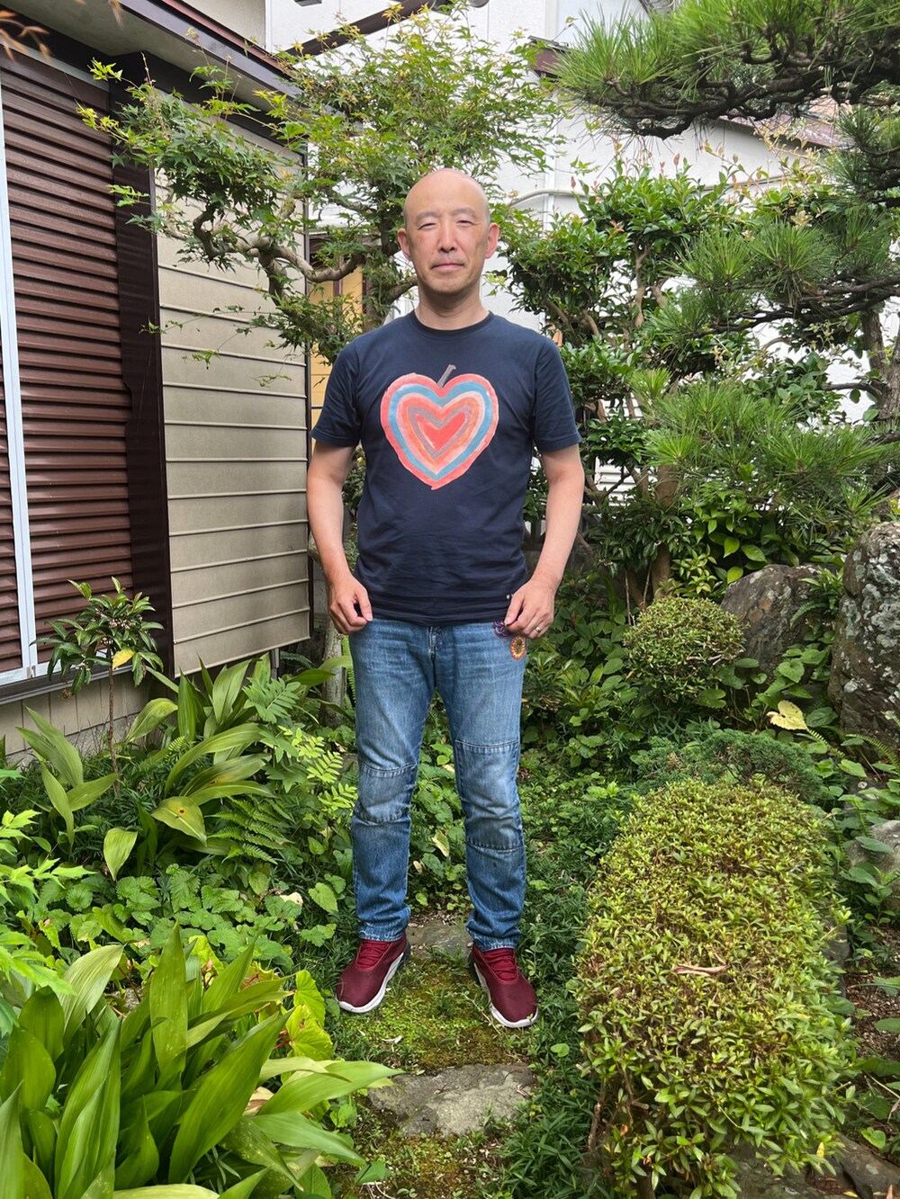 ブラック系のTシャツ/カットソー、ブルー系のデニムパンツ、レッド系のスニーカーを着用したメンズの夏コーディネートの2枚目の写真
