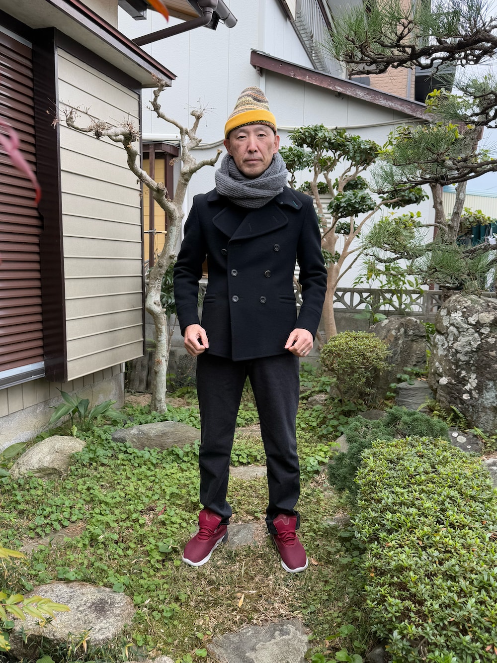 ブラック系のピーコート、ブラック系のパンツ、レッド系のスニーカーを着用したメンズの冬コーディネートの2枚目の写真