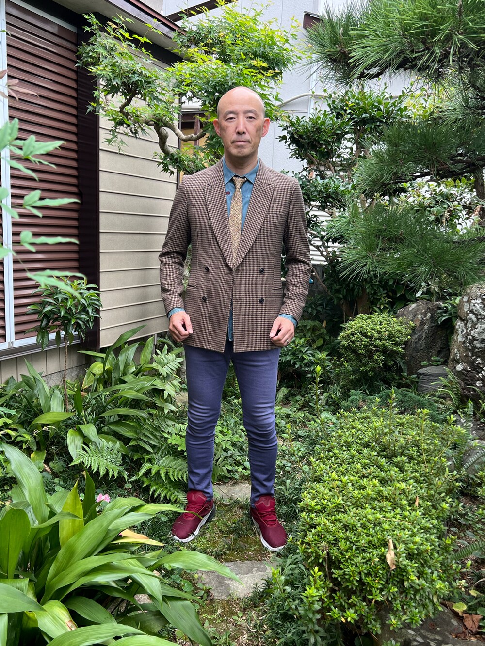 ベージュ系のテーラードジャケット、ブルー系のデニムパンツ、レッド系のスニーカーを着用したメンズの秋コーディネートの3枚目の写真