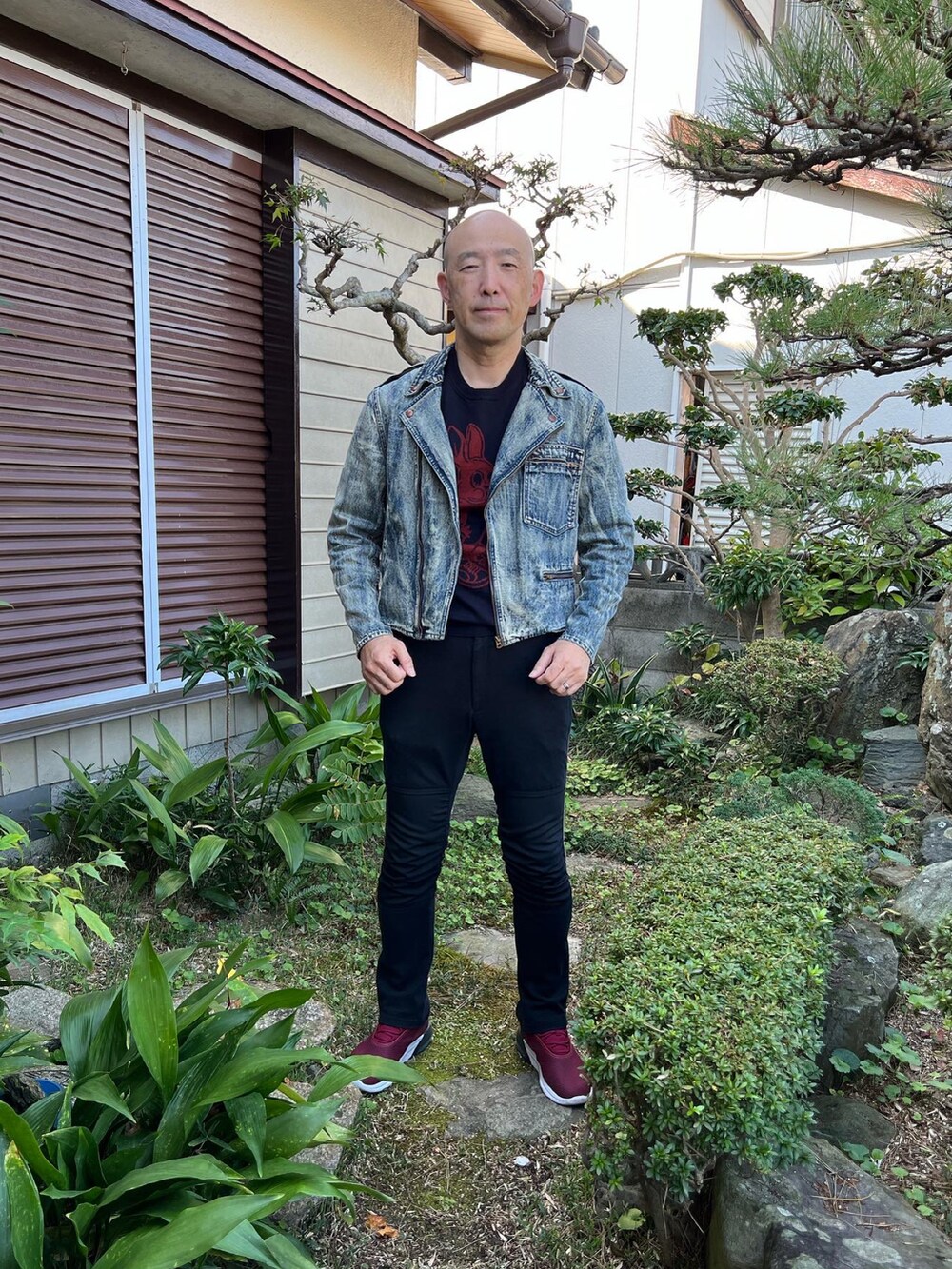 ブルー系のライダースジャケット、ブラック系のパンツ、レッド系のスニーカーを着用したメンズの秋コーディネートの2枚目の写真