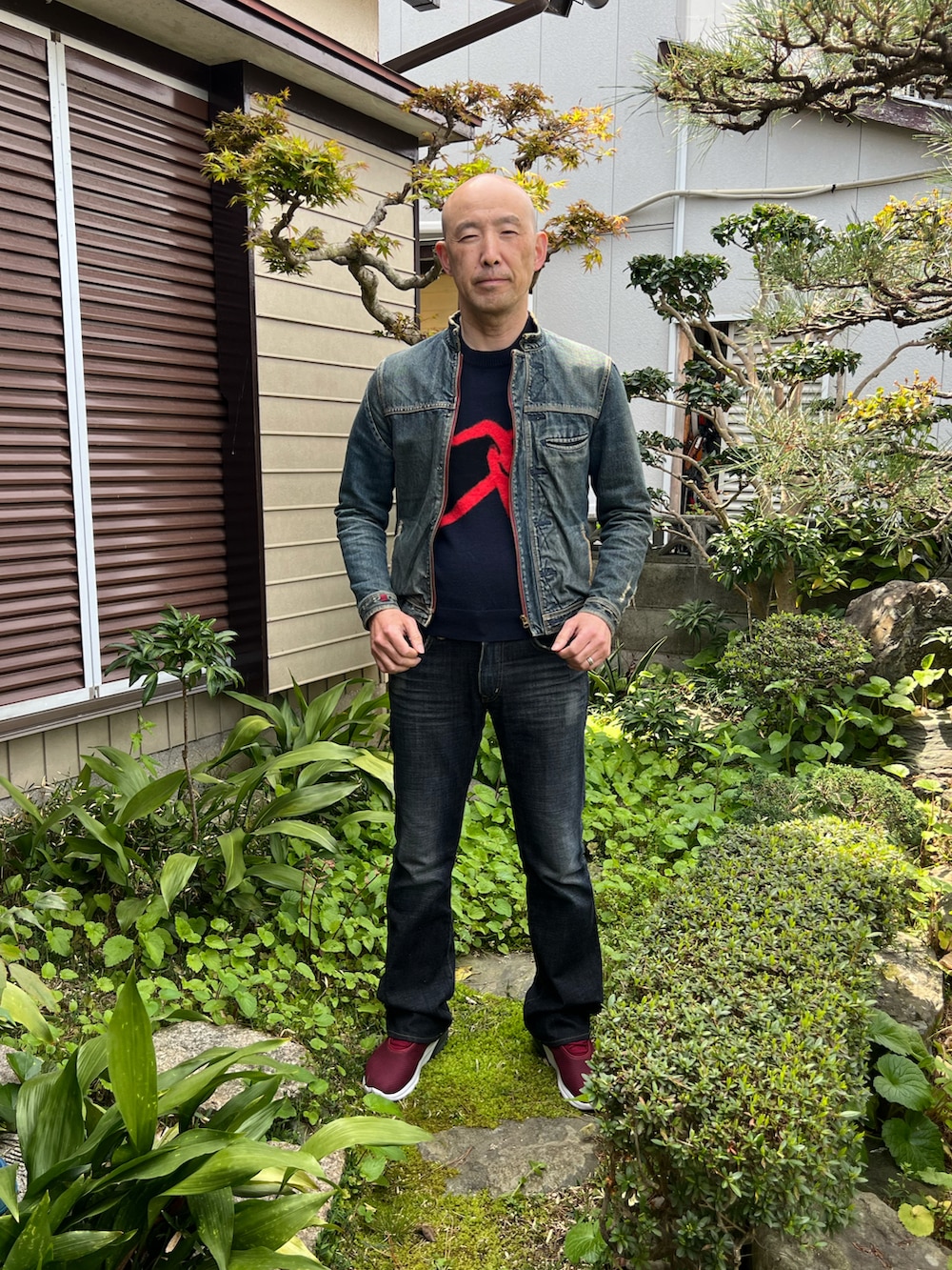 ブラック系のニット/セーター、ブルー系のライダースジャケット、ブラック系のデニムパンツを着用したメンズの春コーディネートの2枚目の写真