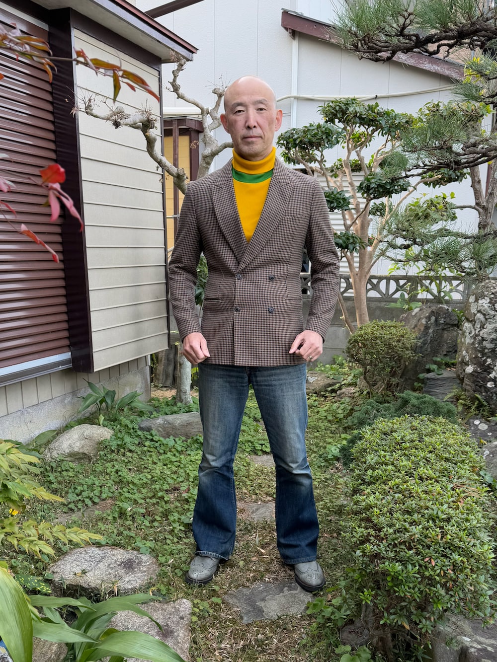 ベージュ系のテーラードジャケット、イエロー系のTシャツ/カットソー、ブルー系のデニムパンツを着用したメンズの冬コーディネートの2枚目の写真