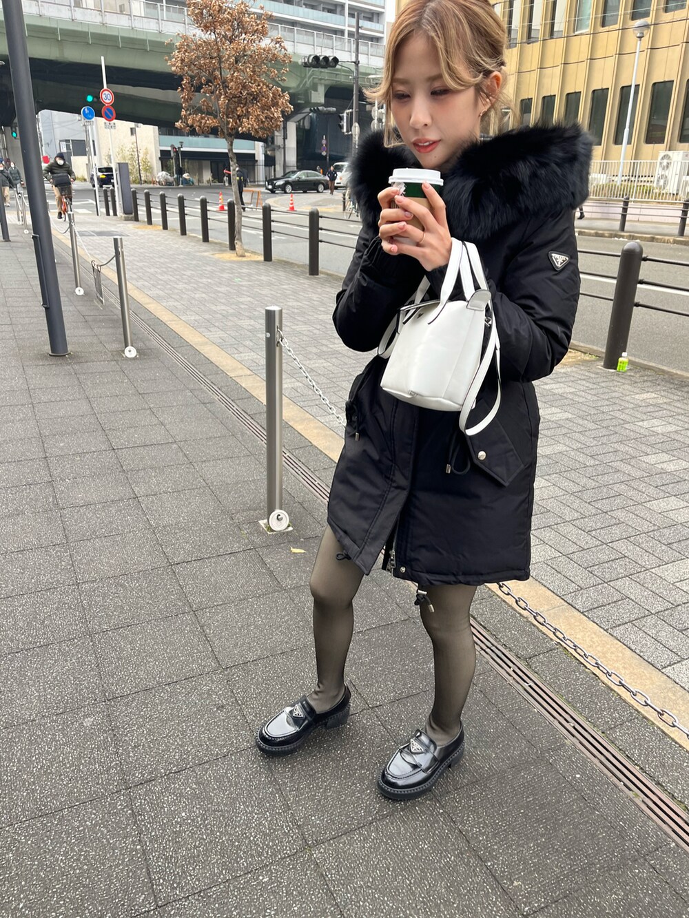 ホワイト系のショルダーバッグ、ブラック系のダウンジャケット/コート、ブラック系のローファーを着用したレディースの冬コーディネートの3枚目の写真