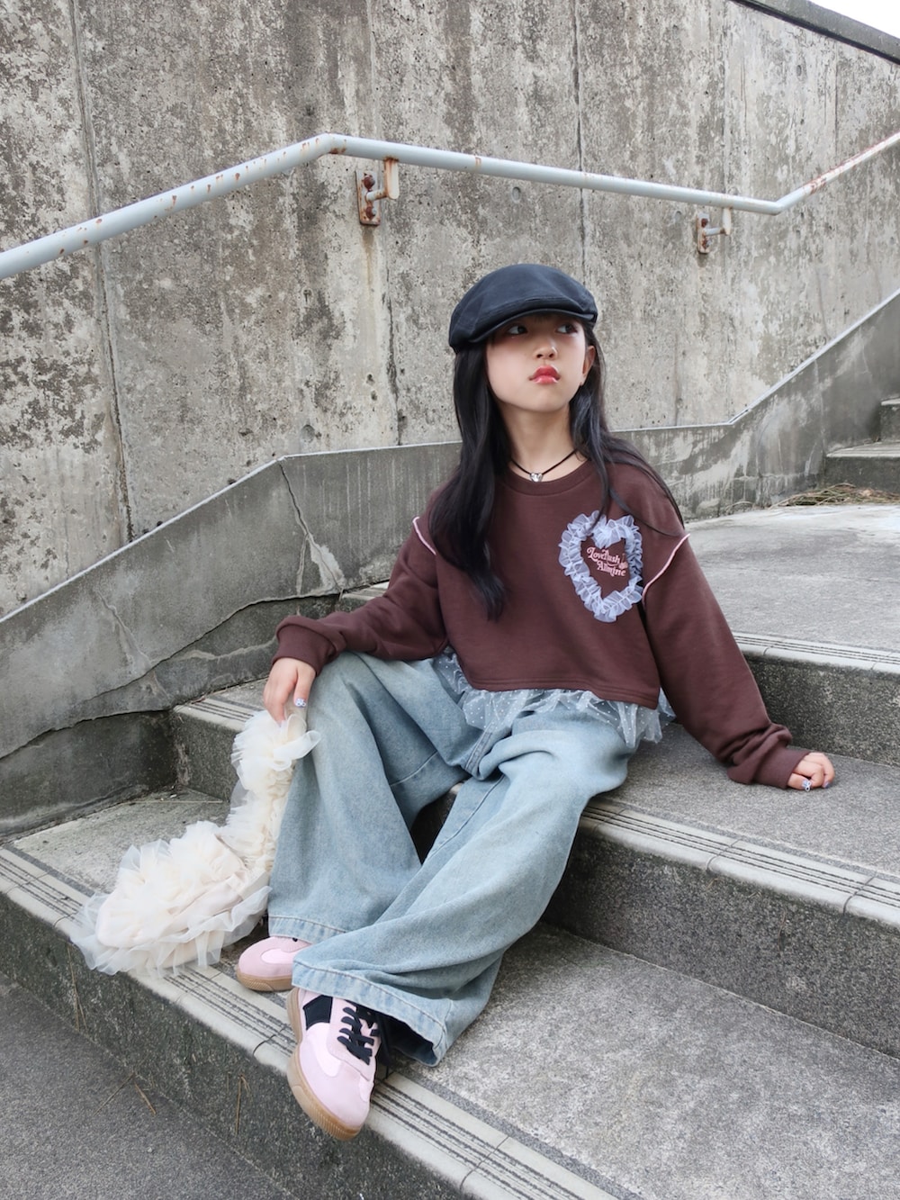 ブラウン系のスウェット、ブルー系のデニムパンツ、ホワイト系のショルダーバッグを着用したキッズの夏コーディネートの2枚目の写真