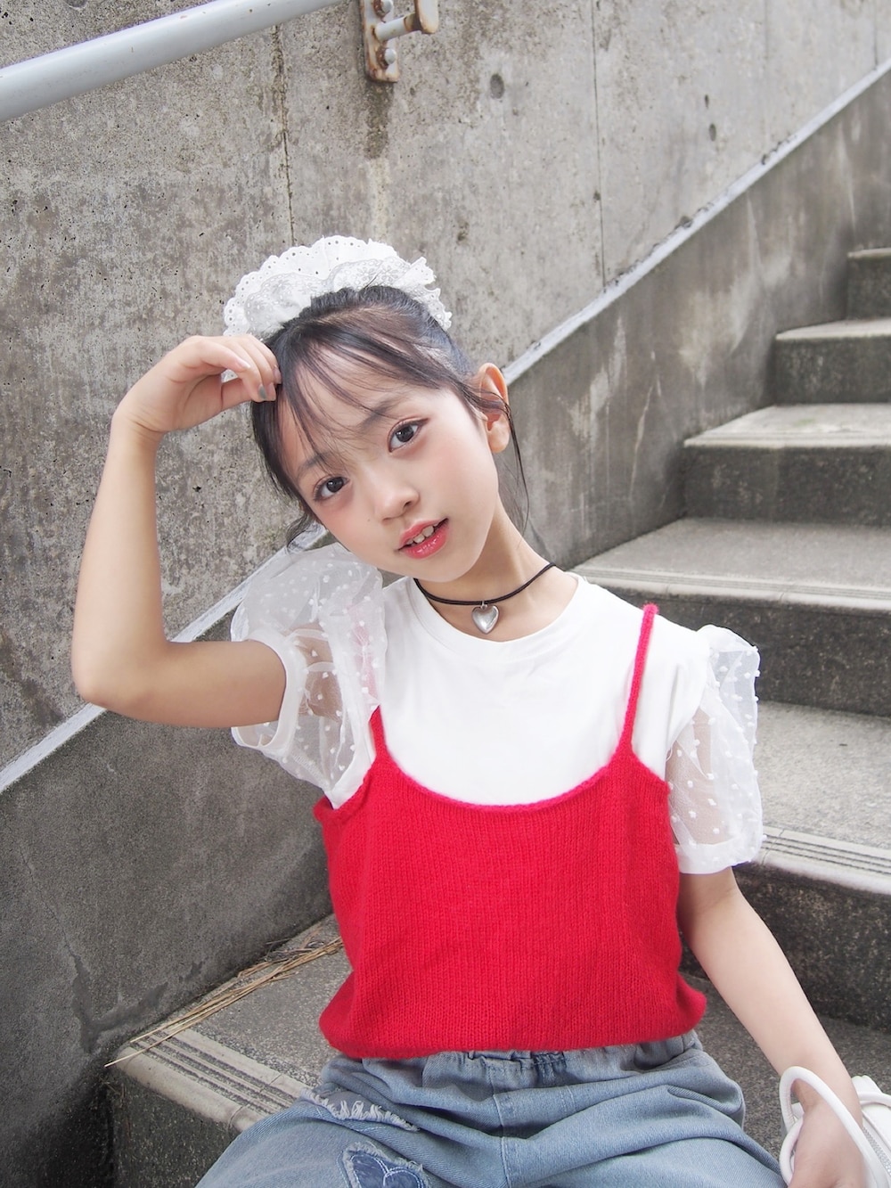 レッド系のキャミソール、ブルー系のデニムパンツ、ホワイト系のシュシュを着用したキッズの春コーディネートの2枚目の写真