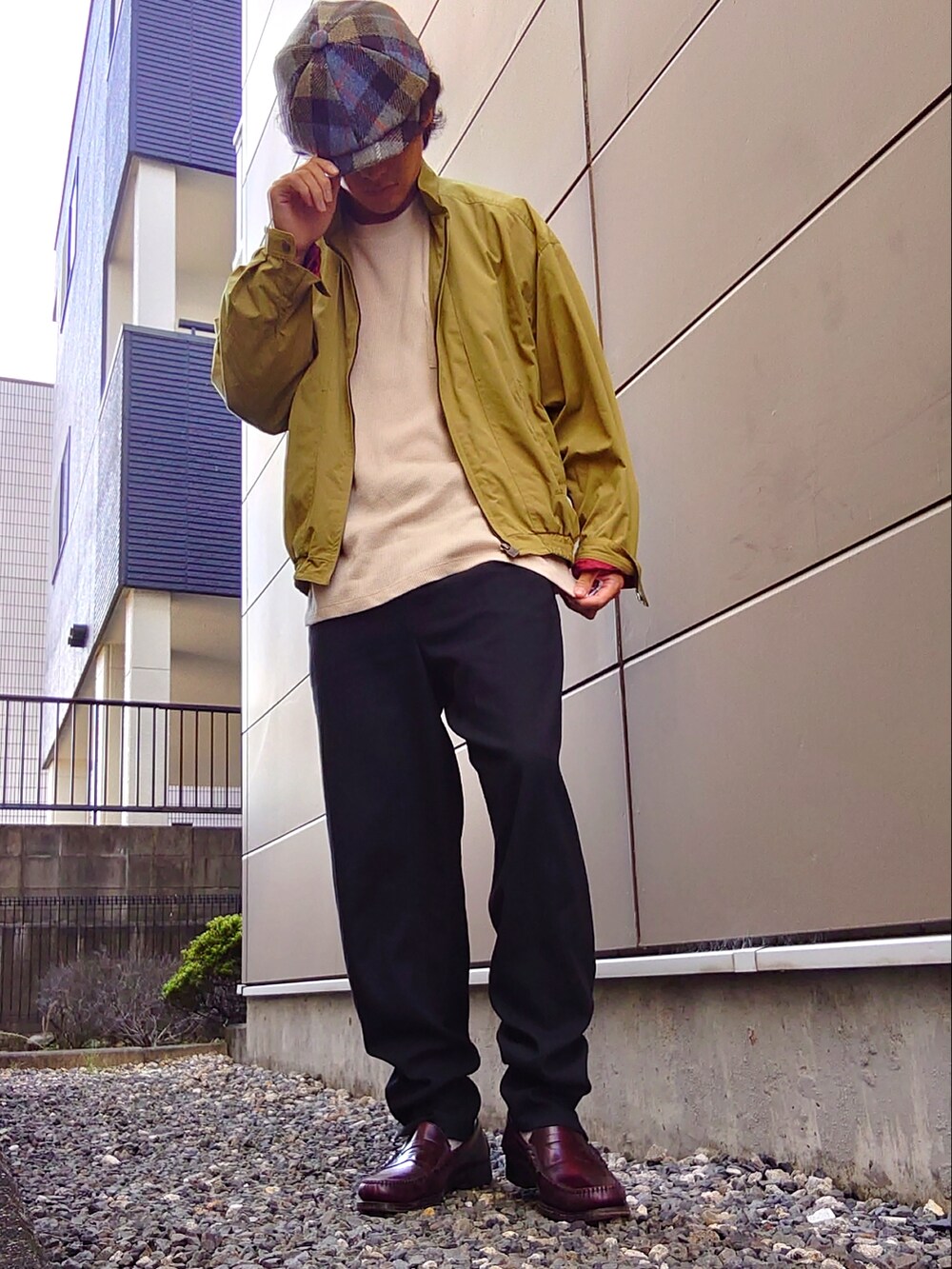 ブラック系のスラックス、イエロー系のブルゾン、ベージュ系のTシャツ/カットソーを着用したメンズの秋コーディネートの2枚目の写真