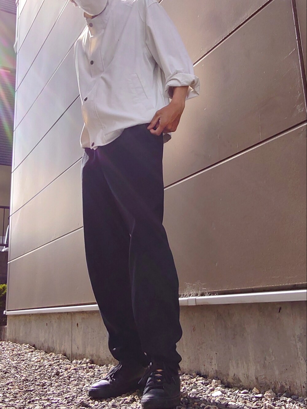 ブラック系のスラックス、ホワイト系のブルゾン、ブラック系のスニーカーを着用したメンズの秋コーディネートの2枚目の写真